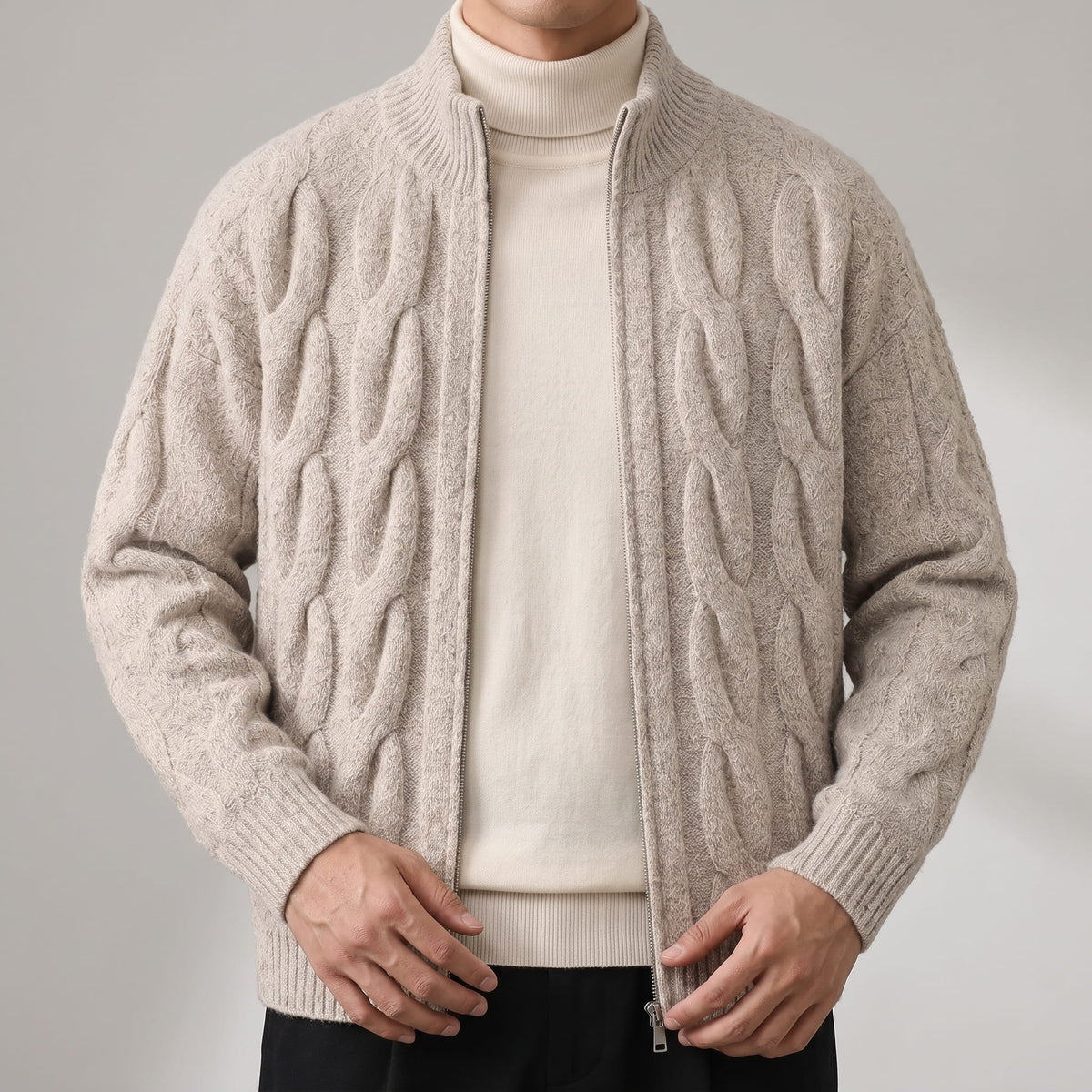 Close-up of the khaki cable knit cardigan open over a cream turtleneck