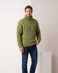 Man wearing men's chunky cable-knit turtleneck sweater in olive green with dark jeans