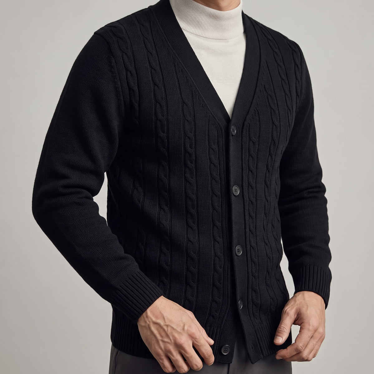Close-up of the black cable knit V-neck cardigan over a cream turtleneck