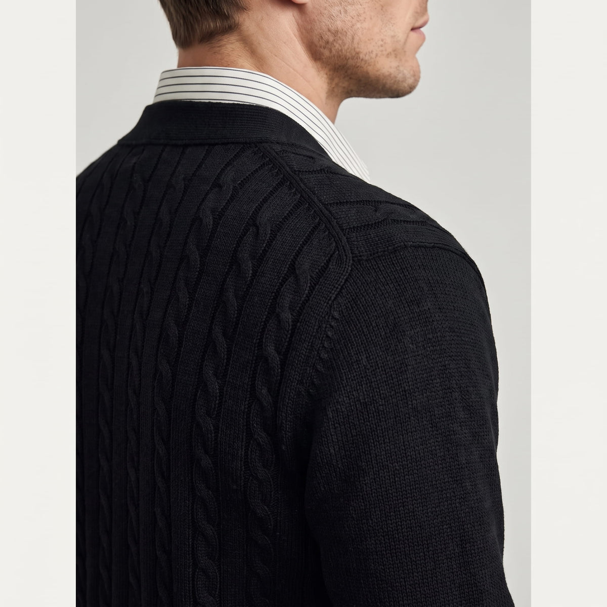 Side profile of the black cardigan showing cable knit at the shoulder