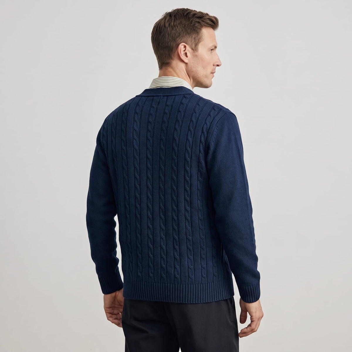 Back view of the navy cable knit cardigan with dark trousers