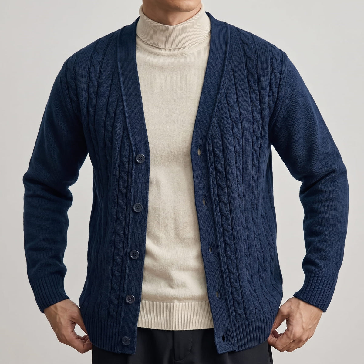 Close-up of the navy cable knit cardigan buttoned over a cream turtleneck