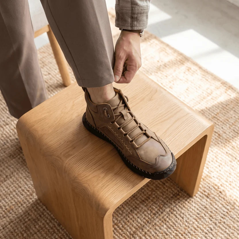 Man lacing a camel wide toe box hiking boot with his foot on a wooden stool