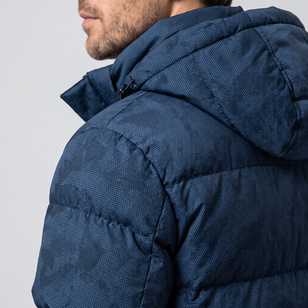 Close view of the navy hood and shoulder, camo print visible in the weave