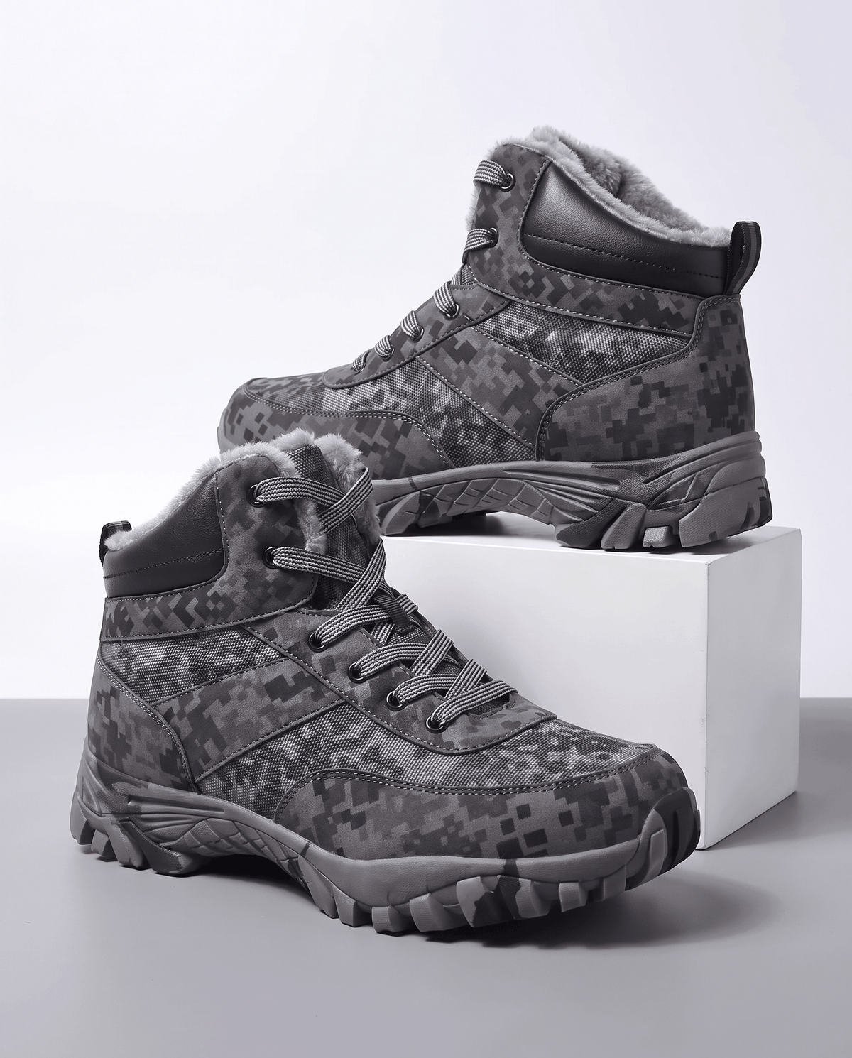 Men's camo winter hiking boots in black camo with fleece collar, on a white block