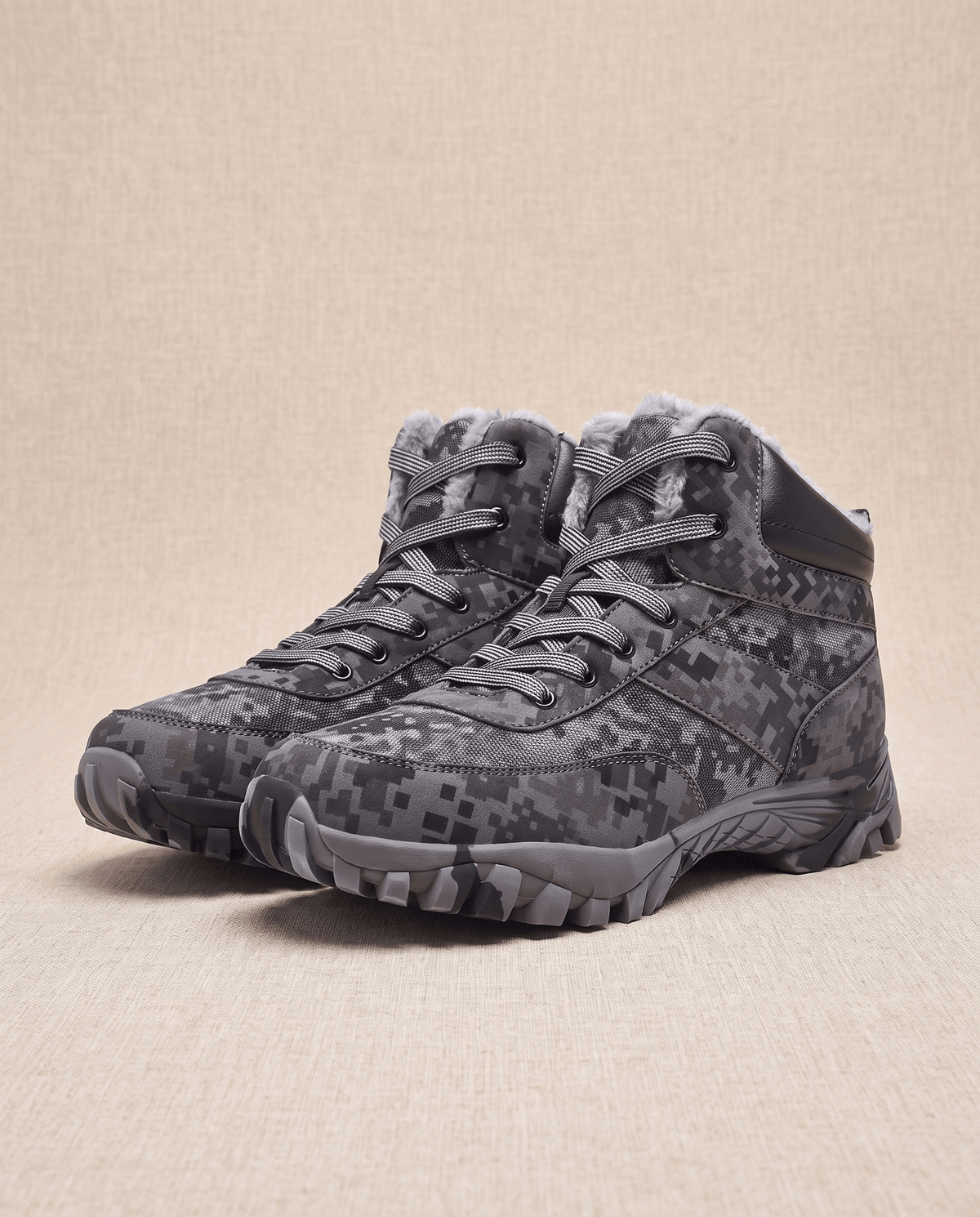 Dark camo pair angled on a warm backdrop showing the deep lug outsole