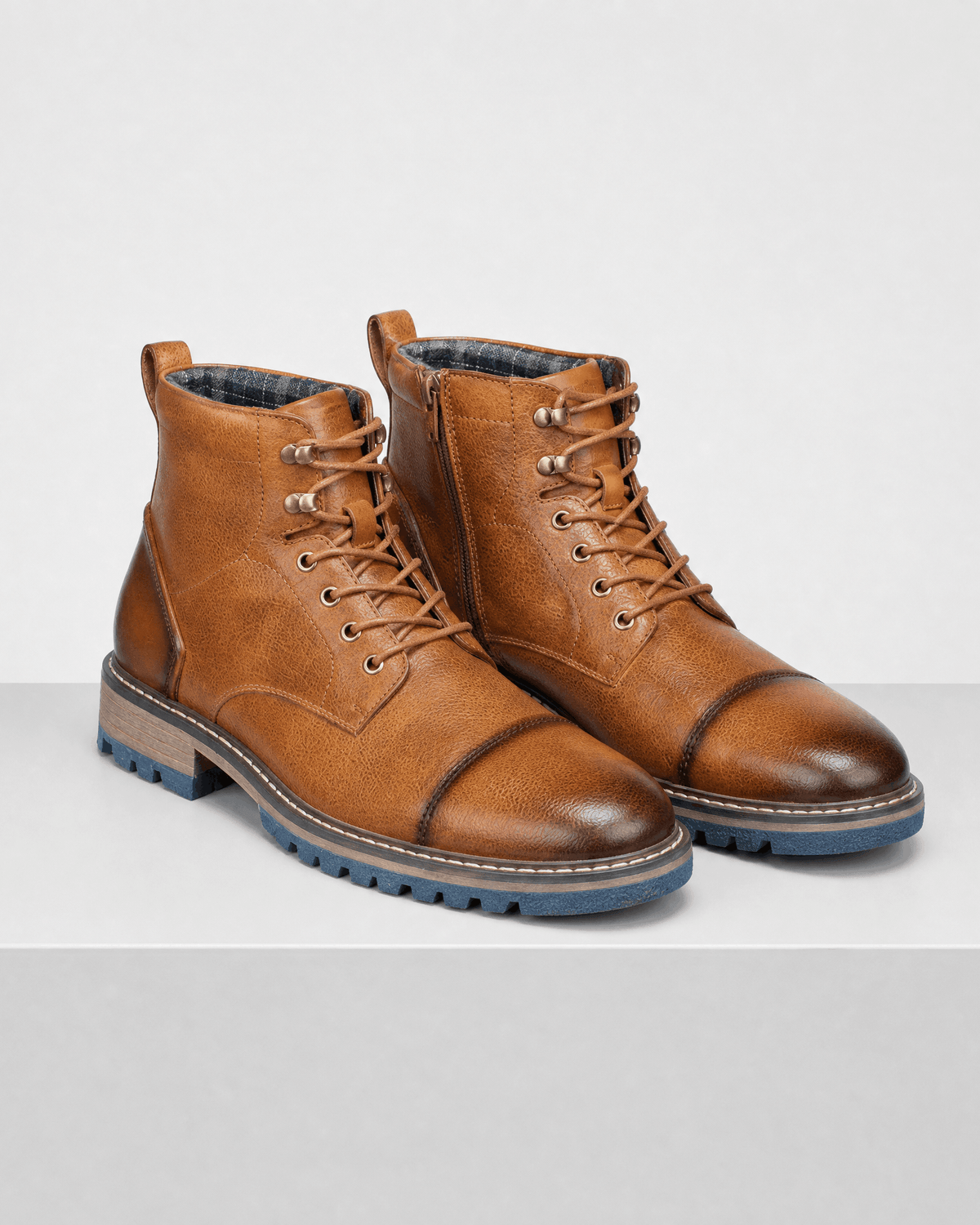Brown smooth grain leather cap toe boots featuring lace-up fronts, side zip entries, and rugged blue lug outsoles.