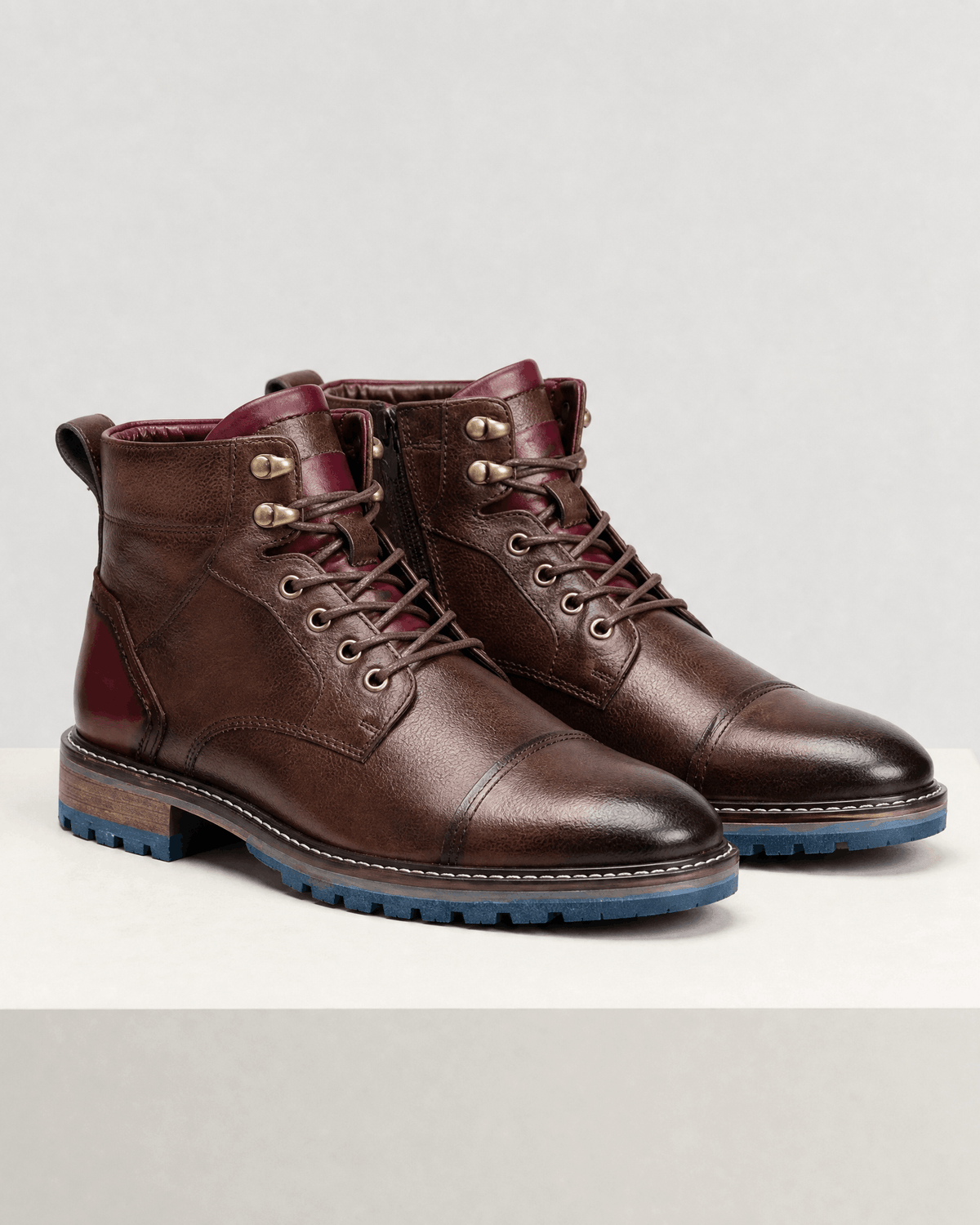 Dark brown smooth grain leather cap toe boots with side zip, hook lacing, and a blue treaded lug outsole.