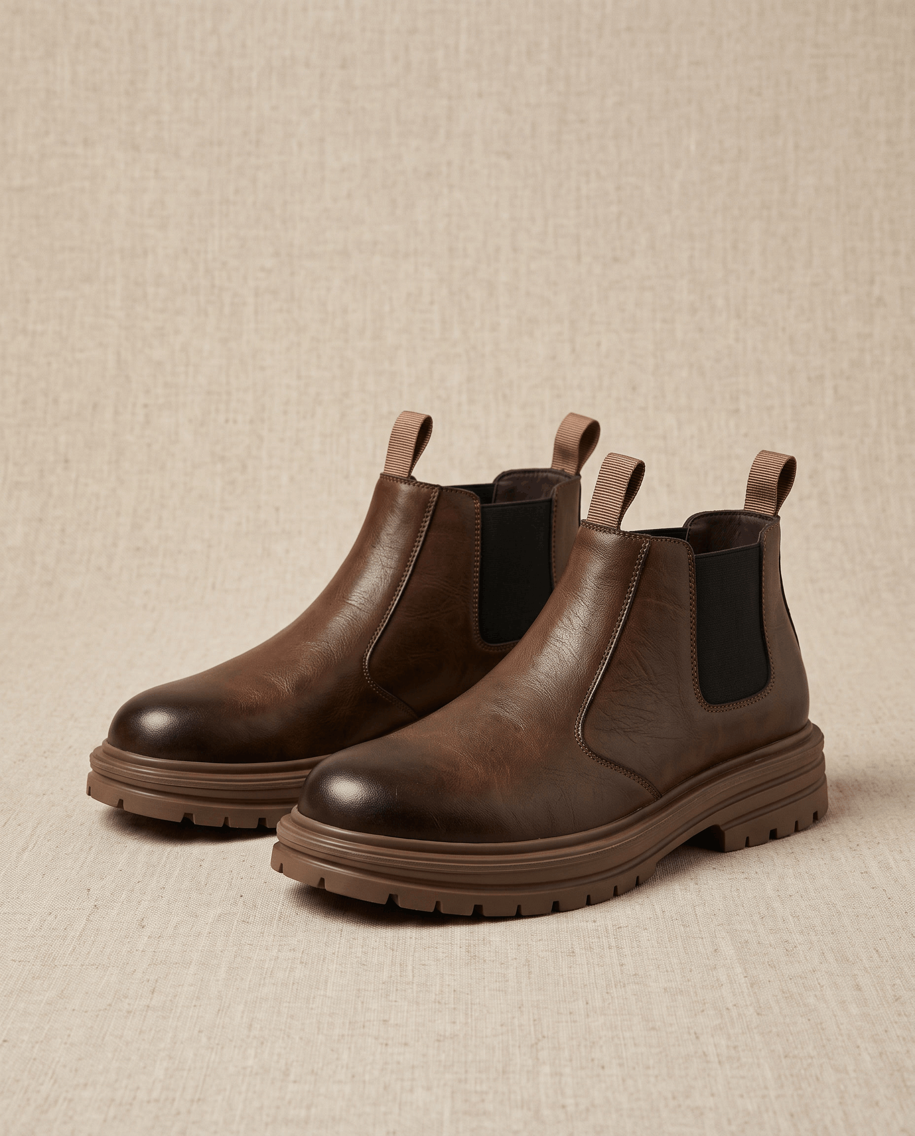 Brown leather Chelsea boots with elastic side panels, twin pull tabs, and a chunky lugged platform rubber sole.