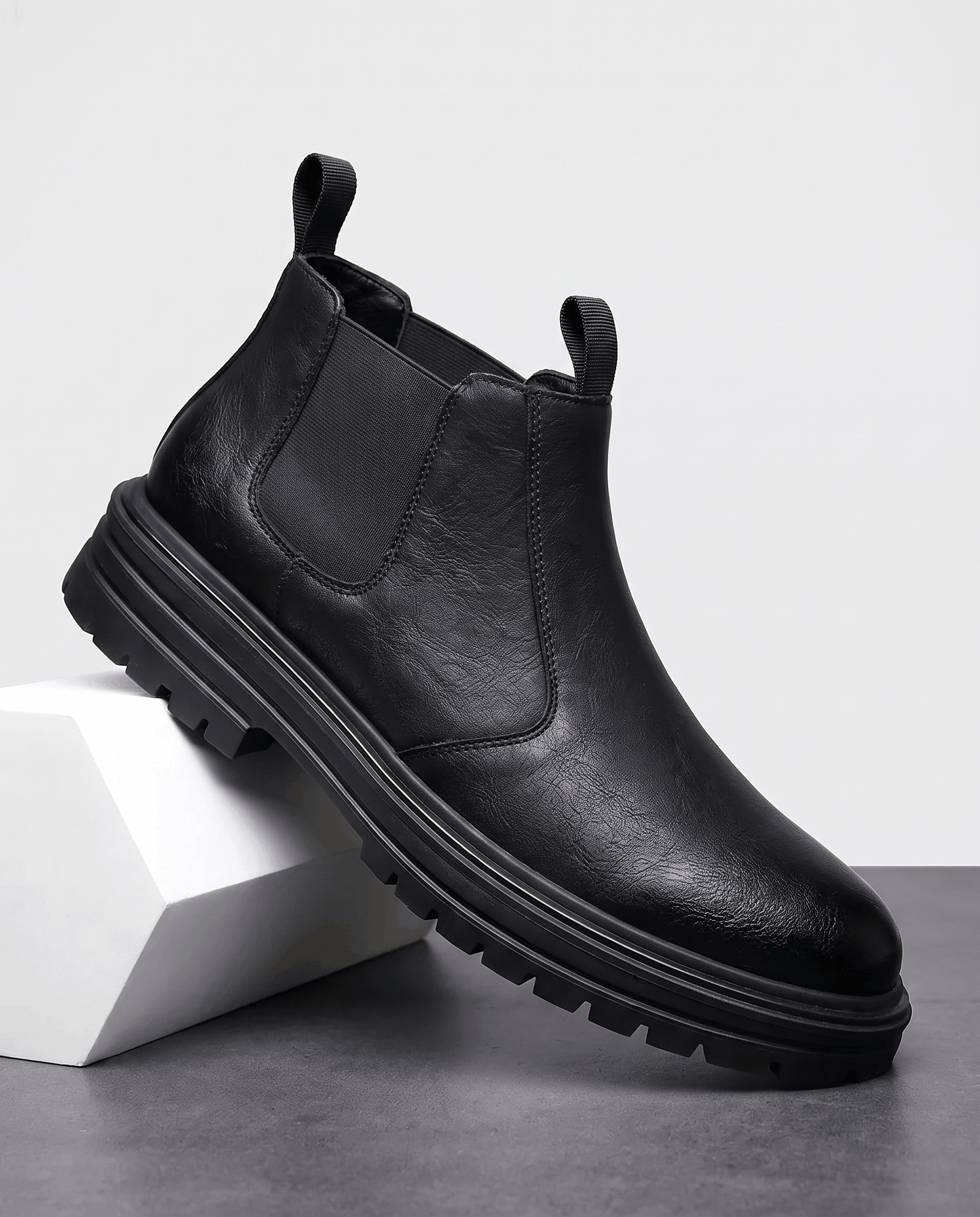 Black pebbled leather Chelsea boots with elastic side panels, twin pull tabs, and a chunky lugged platform rubber sole.