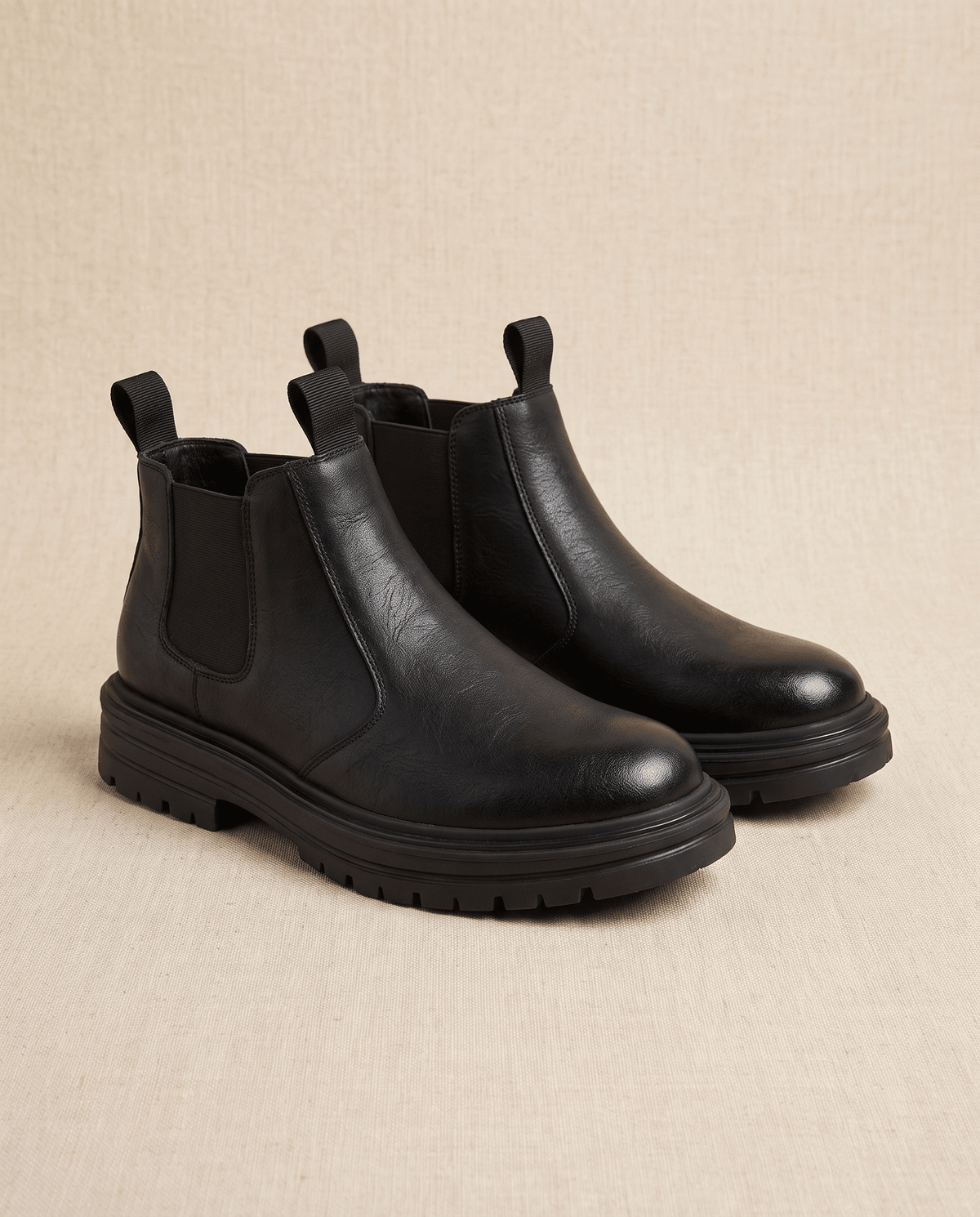 Black pebbled leather Chelsea boots with elastic side gores, twin pull tabs, and a thick lugged platform rubber sole.