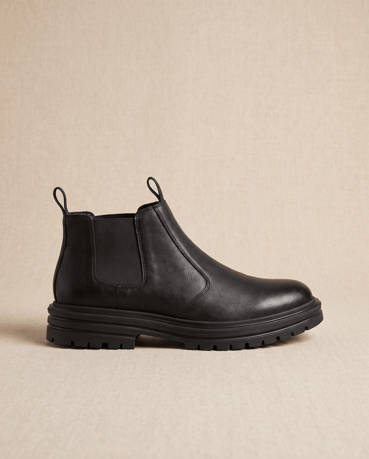 Black pebbled leather Chelsea boots with elastic side gores, twin pull tabs, and a chunky lugged platform rubber sole.