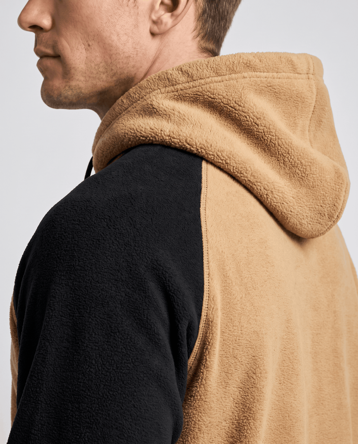 Side close-up of camel hood and black raglan sleeve with soft texture