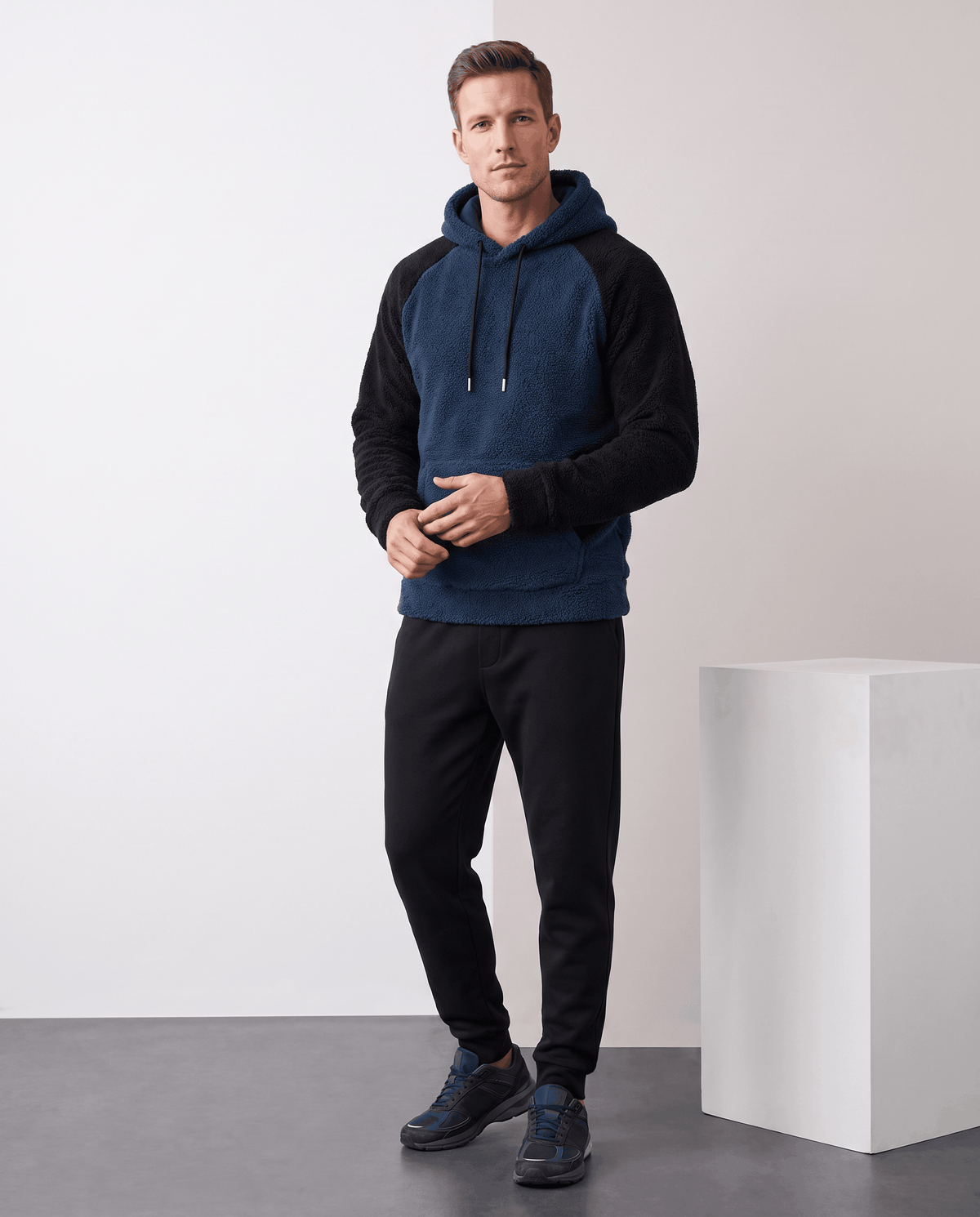 Full-length view of navy blue and black hoodie styled with black pants and sneakers