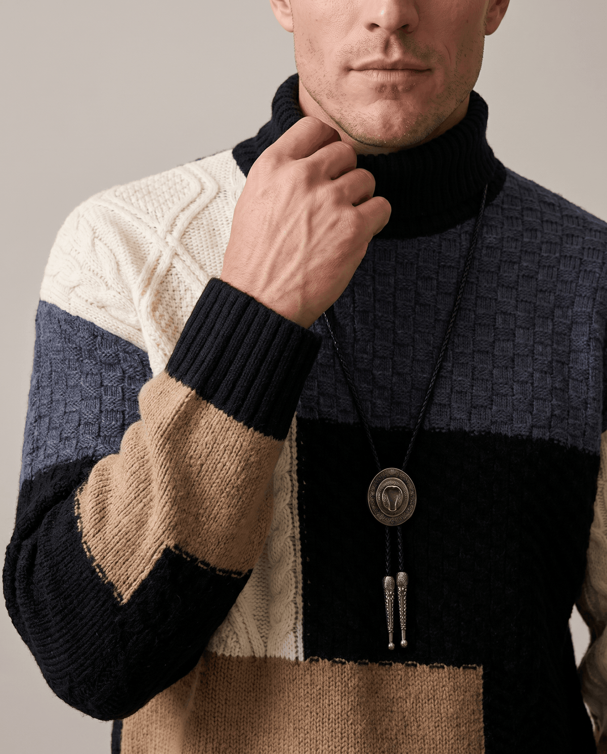 Hand at the black ribbed mock neck of a colorblock chunky sweater