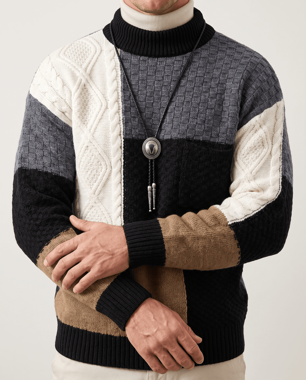 Front close-up of black patchwork knit with cream cable sleeve and pendant necklace