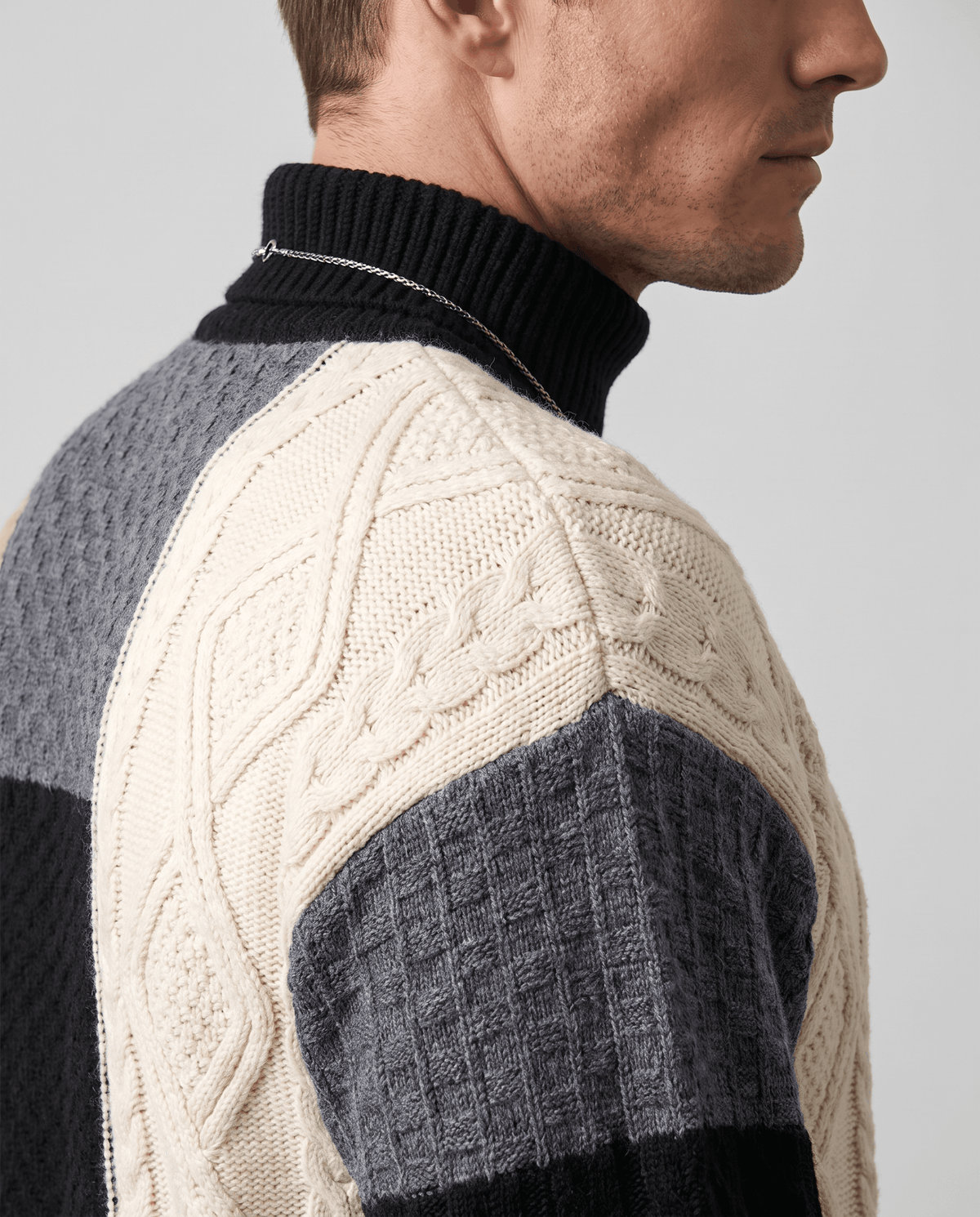 Shoulder close-up of cream cable-knit panel and black ribbed mock collar