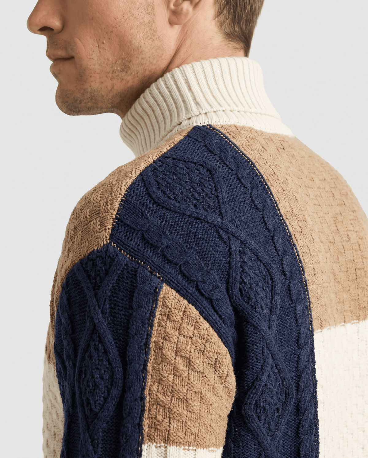 Side close-up of navy cable-knit sleeve and tan shoulder panel