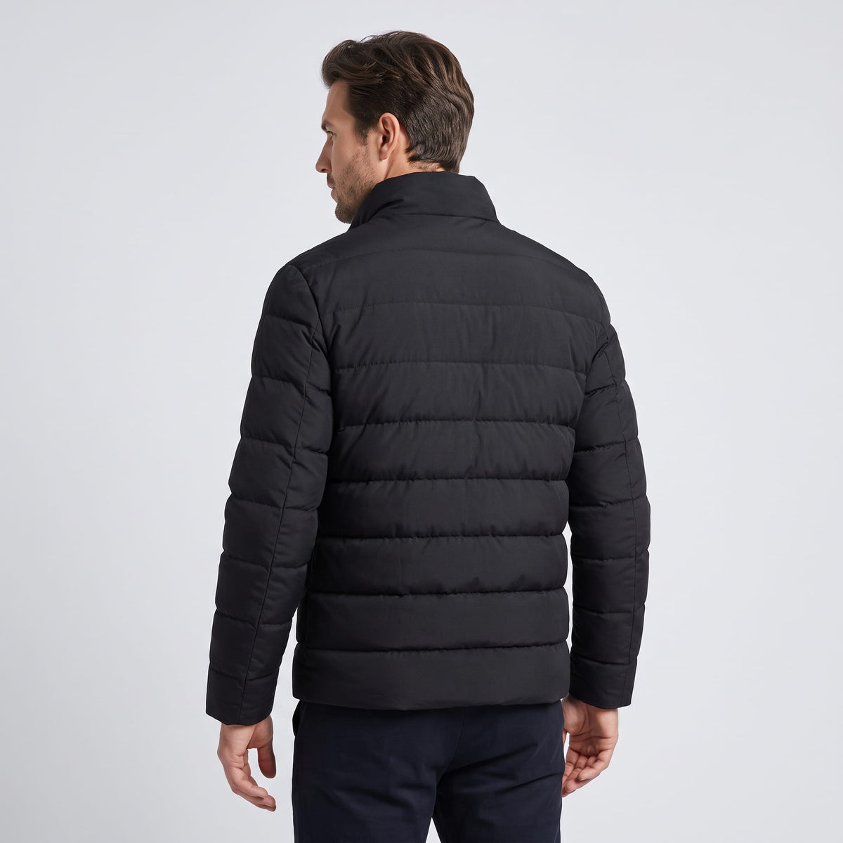 Back view of the all-black jacket showing quilted channels and plain hem