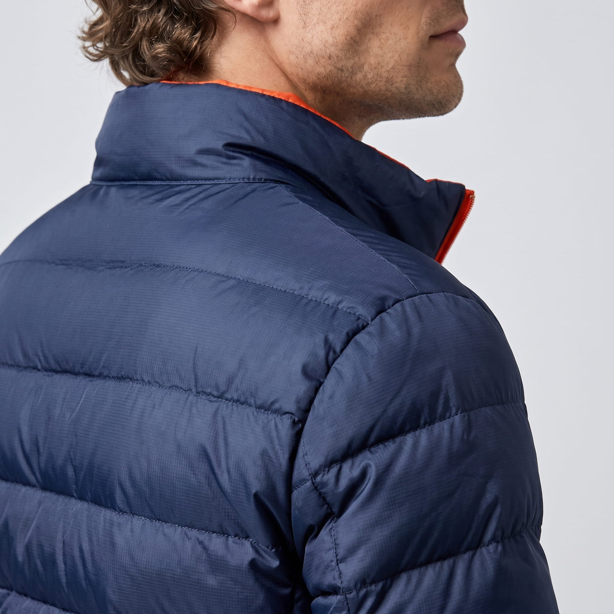 Navy shoulder detail with a flash of orange collar lining behind the neck