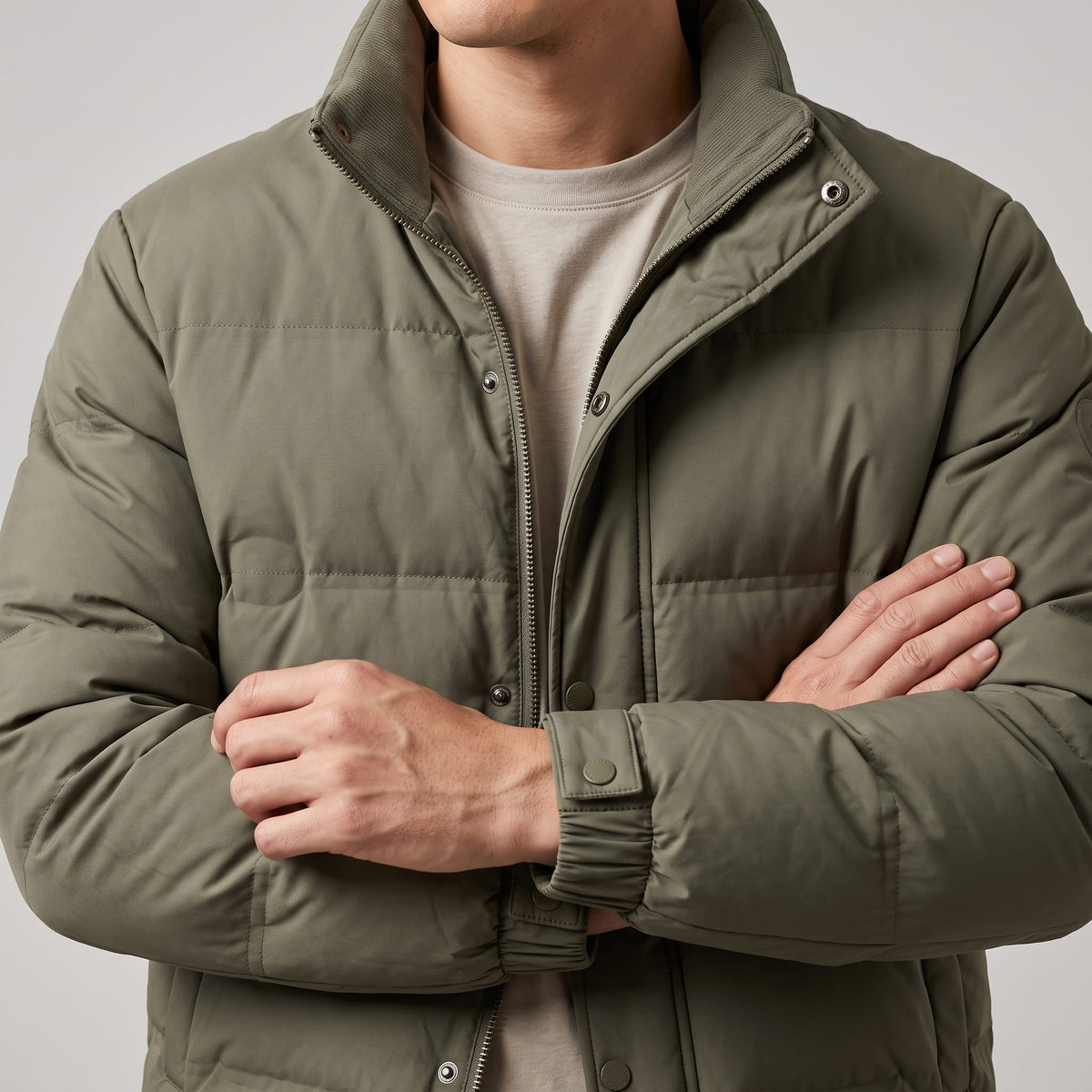 Olive jacket with arms crossed, pillowed quilting and snap cuff in view