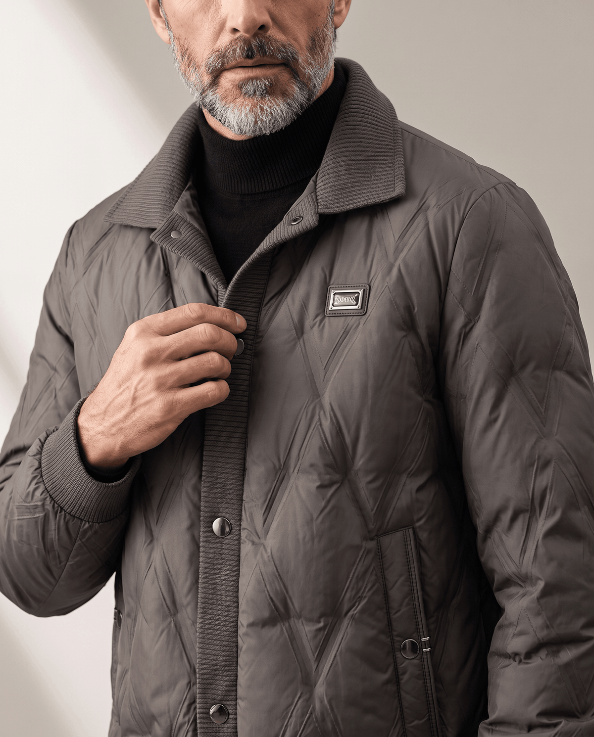 Man touching the snap-button front of a dark brown diamond quilted puffer jacket