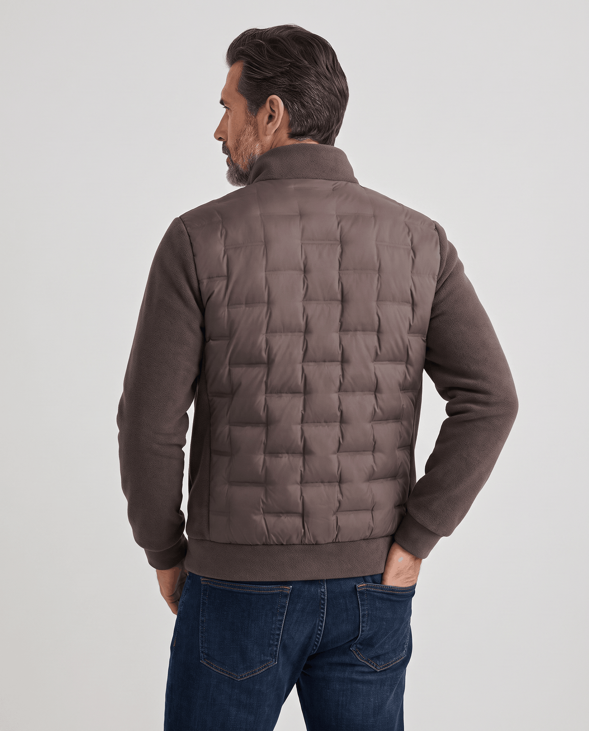 Back view of a man wearing a dark brown quilted hybrid puffer jacket