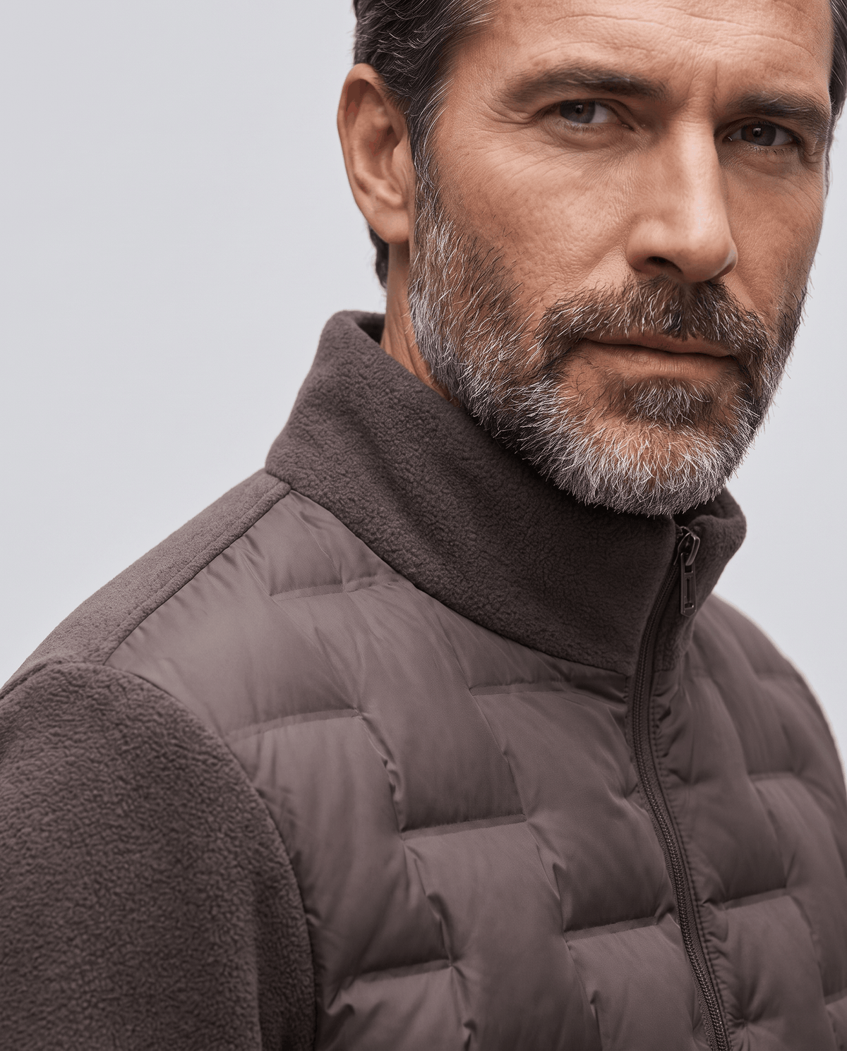 Close-up of the stand collar and fleece sleeve on a dark brown puffer jacket