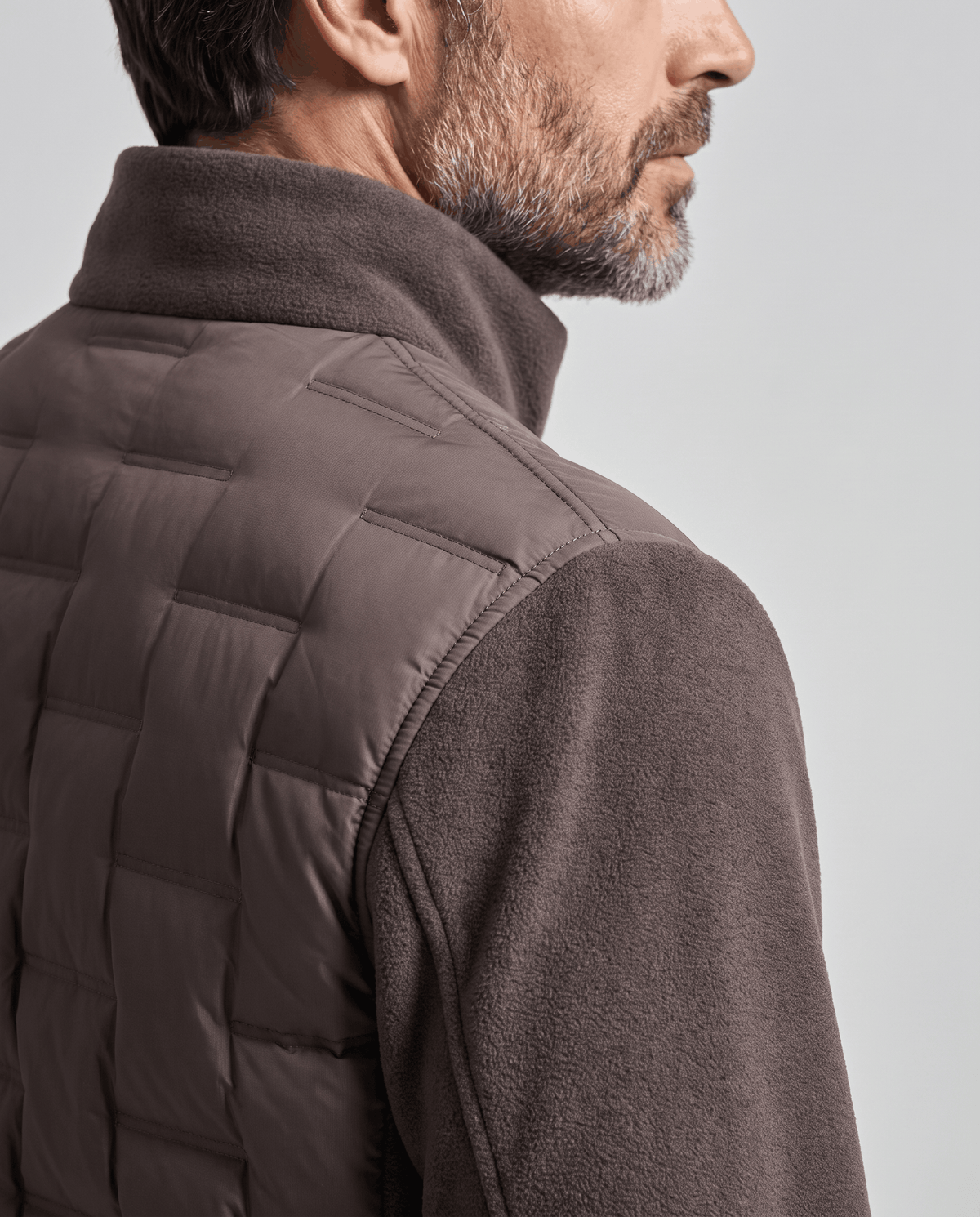 Close-up of the quilted panel and fleece sleeve on a dark brown puffer jacket