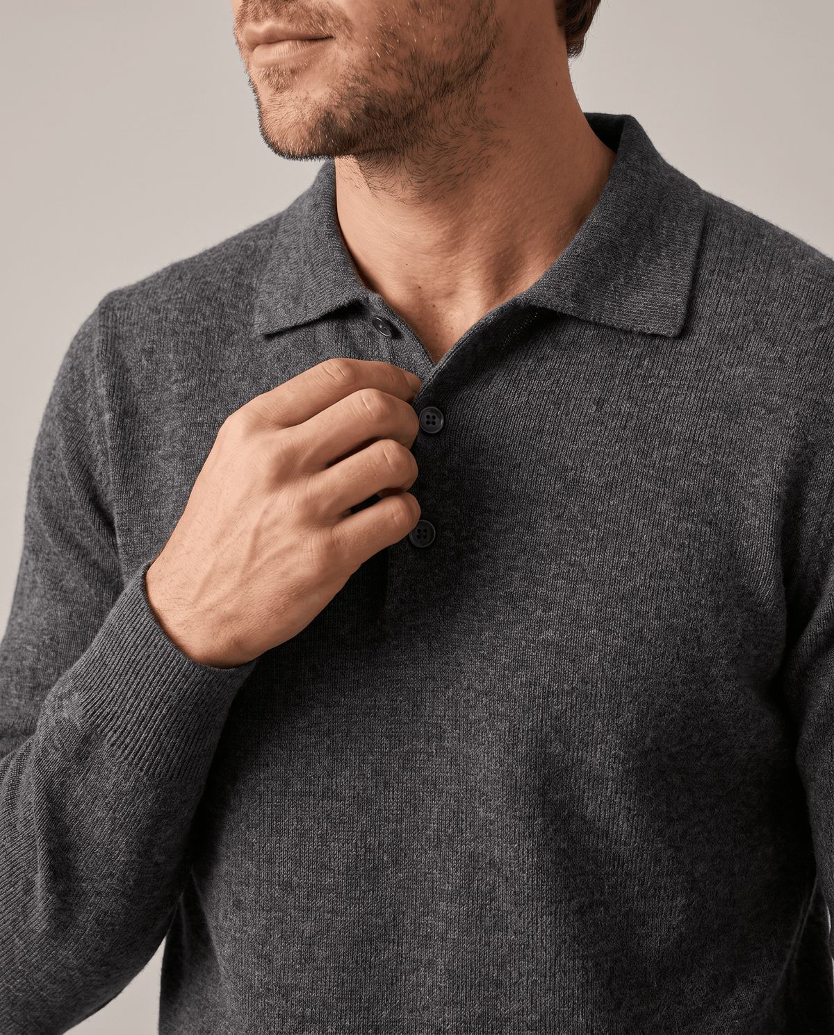 Hand on the button placket of the Elias dark gray wool knit polo sweater
