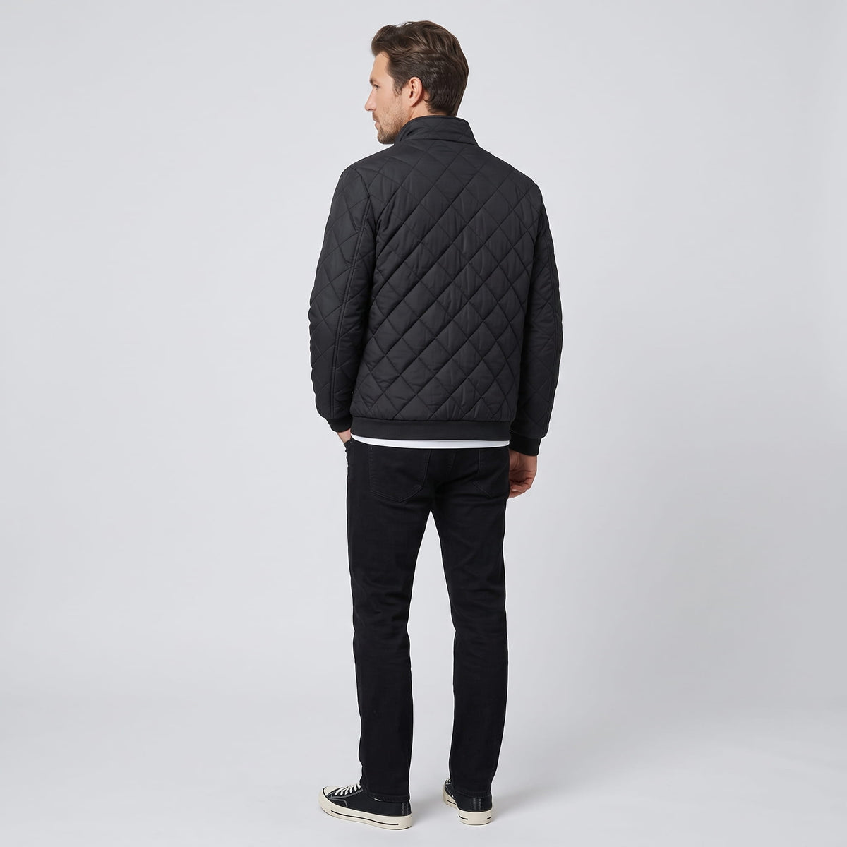 Full back view of the black jacket showing diamond quilting and ribbed hem