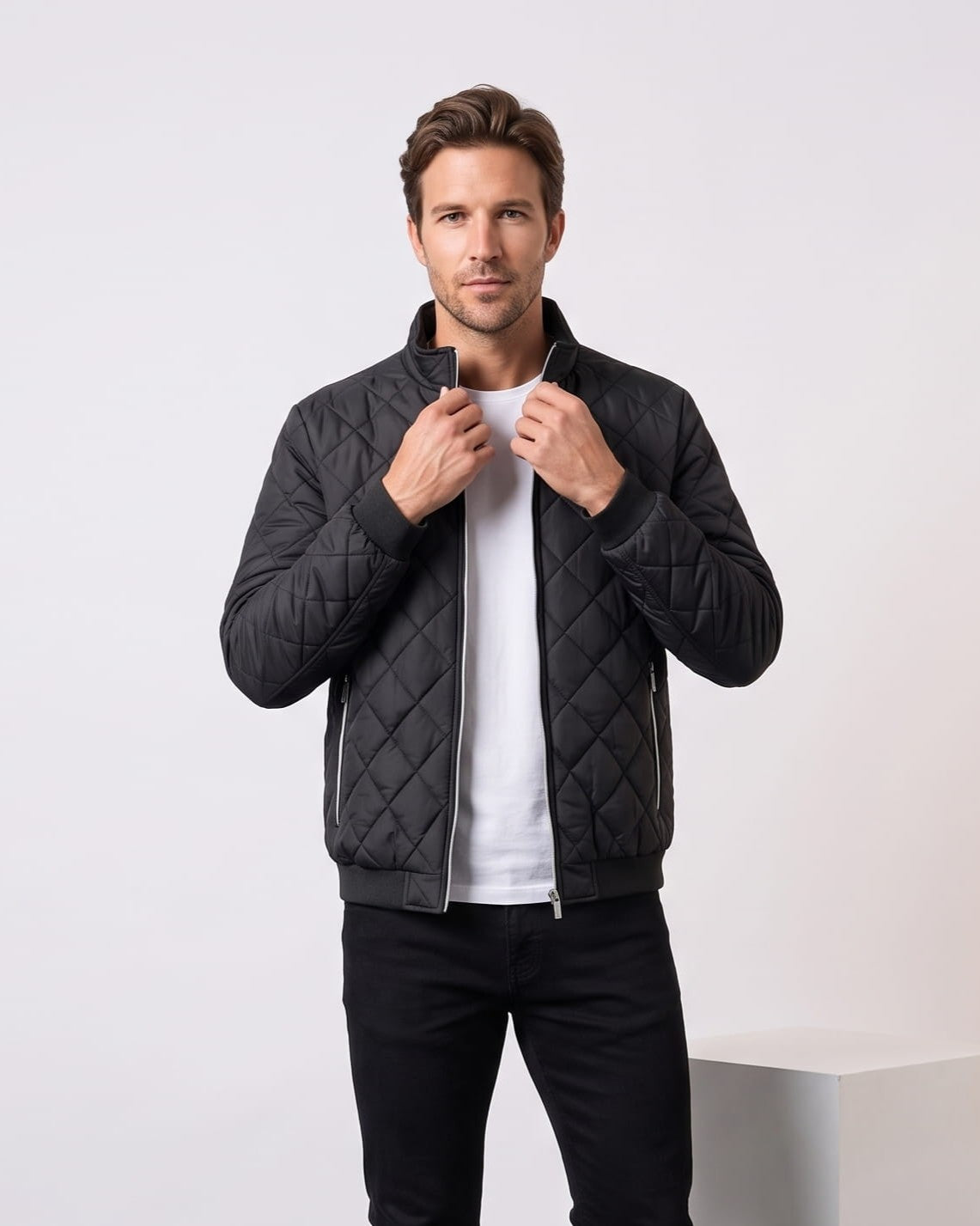 Man wearing black diamond-quilted bomber jacket with stand collar, holding the collar