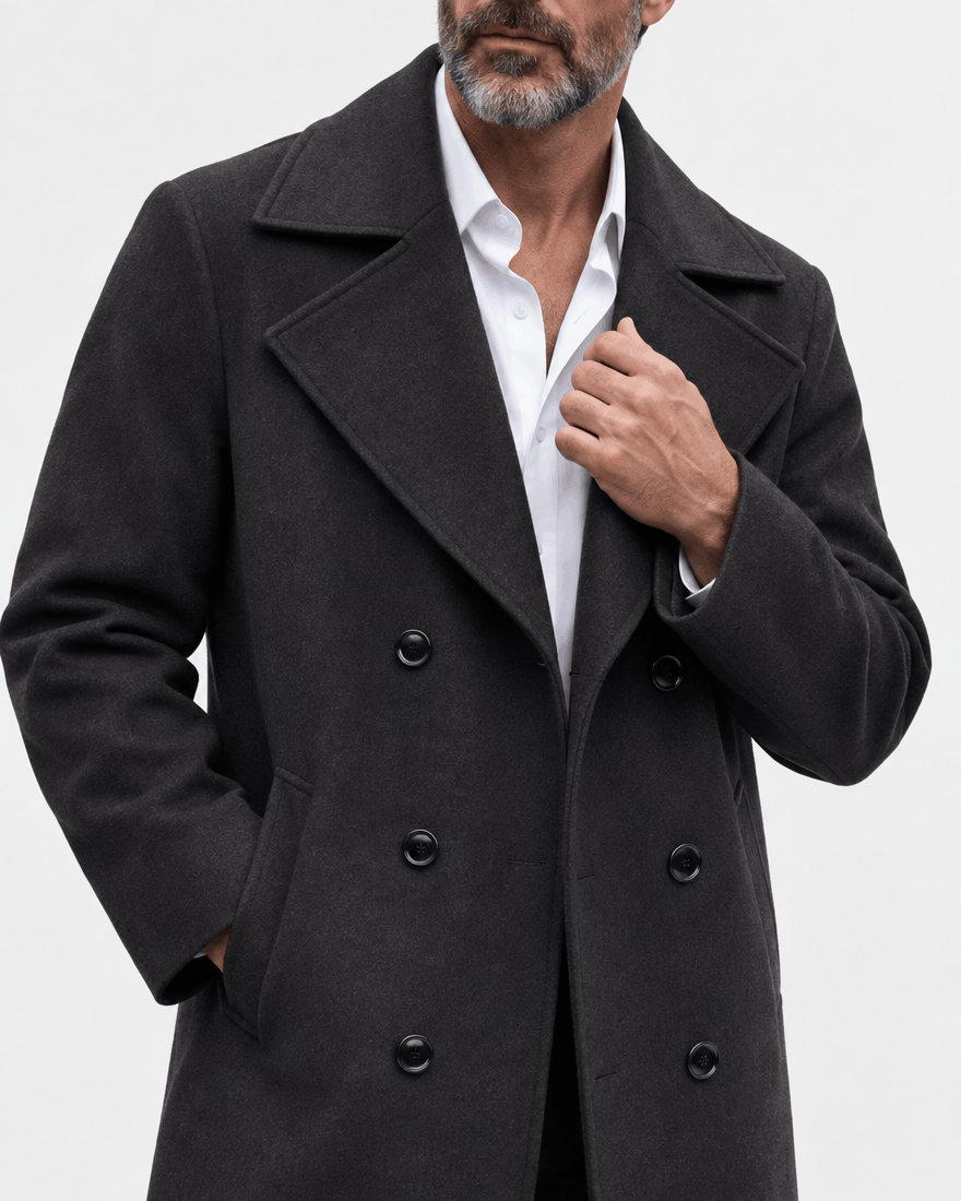 Close-up of the black coat's wide lapel, button rows and textured fabric with a hand at the collar