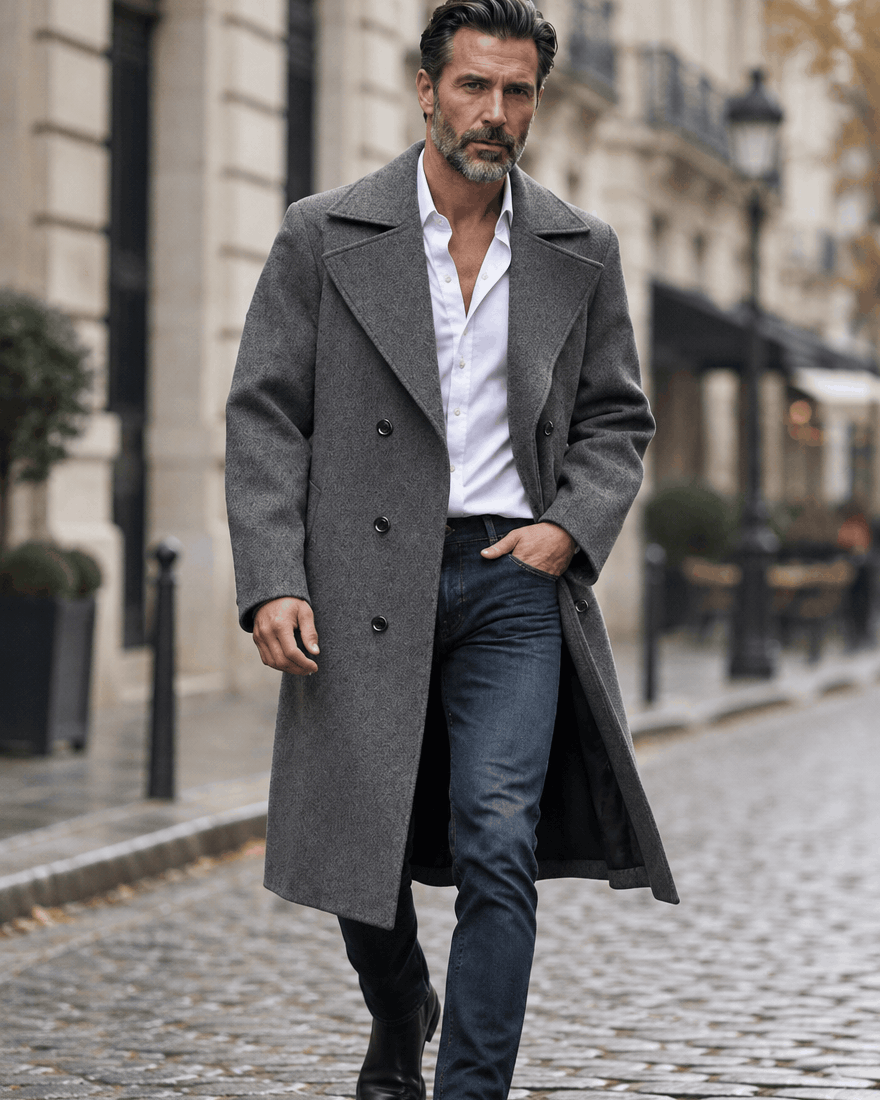 Man walking on a city street in a dark gray overcoat, white shirt and blue jeans
