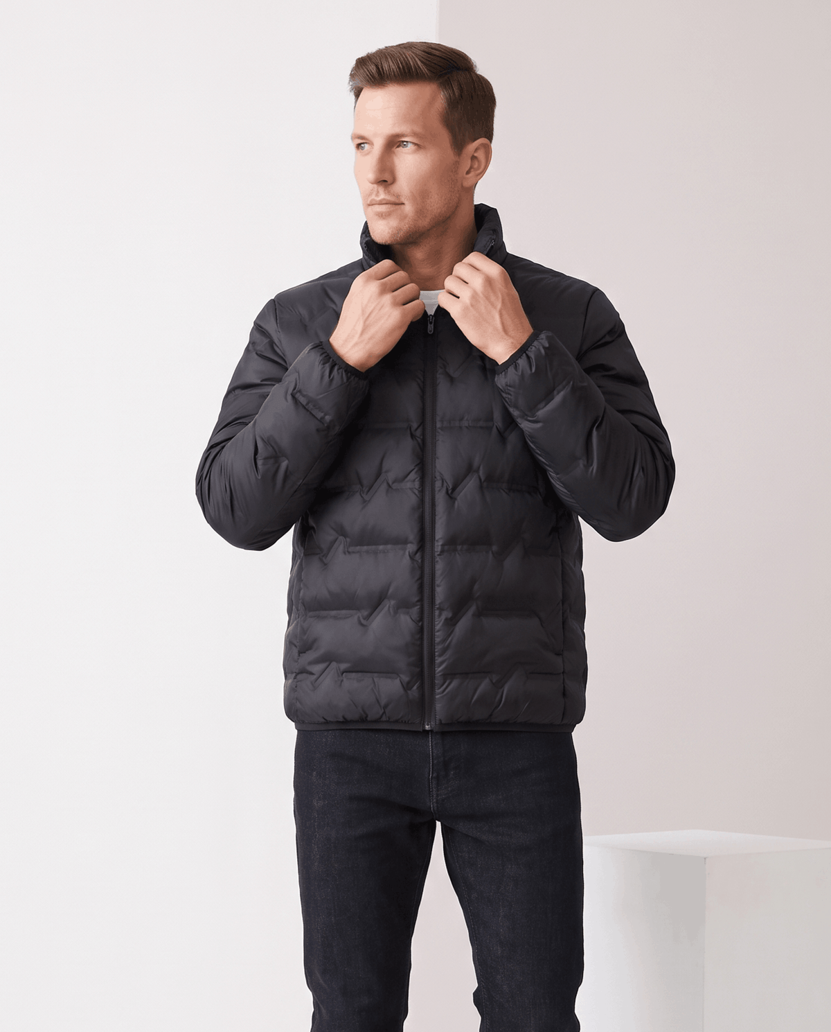 Black colorway worn zipped, both hands lifting the stand collar closed