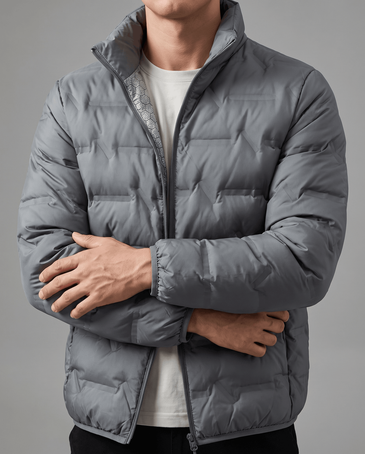 Gray jacket zipped with arms crossed, showing chevron quilting across the chest