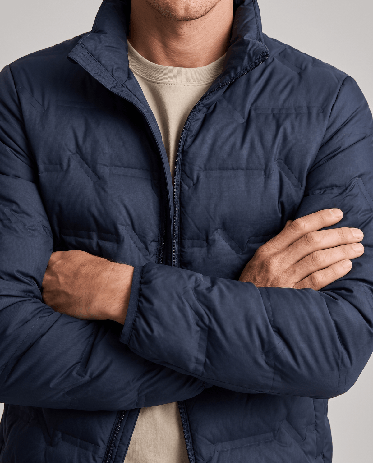 Navy jacket with arms crossed, quilted sleeve and chest panels in close view