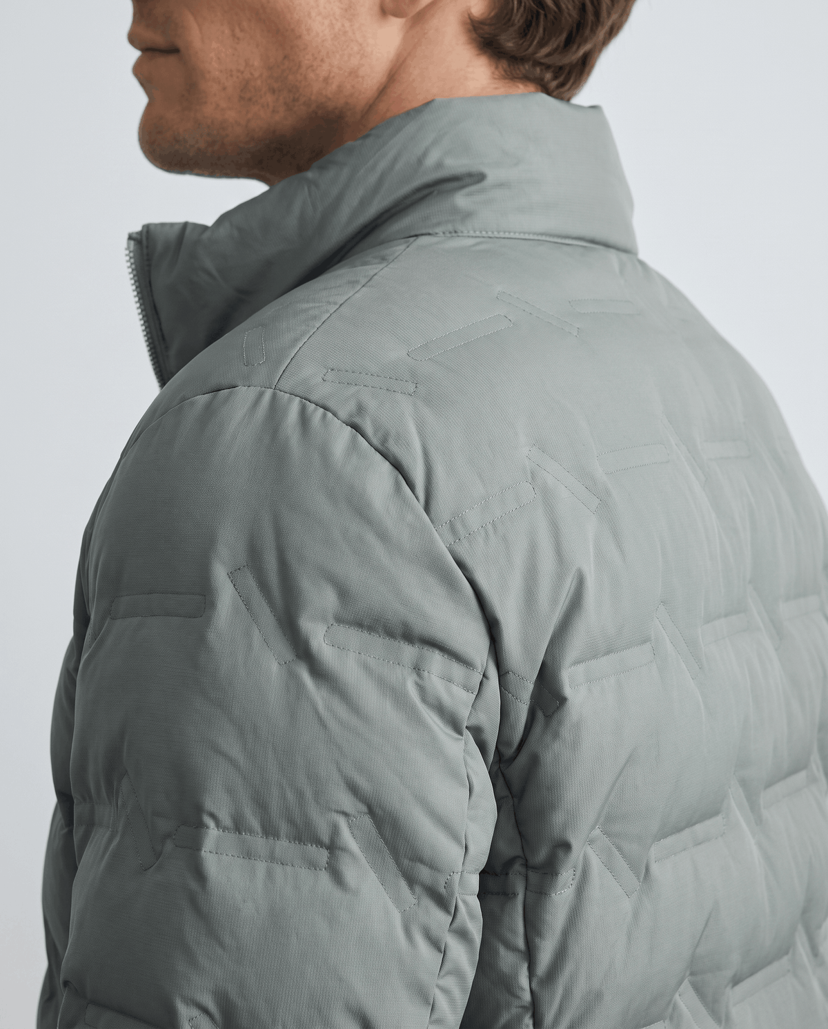 Close olive shoulder detail with quilted channels running across the upper back