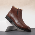 Brown leather ankle boot with basketweave embossed panels, side zip, and a low stacked heel with a squared toe.