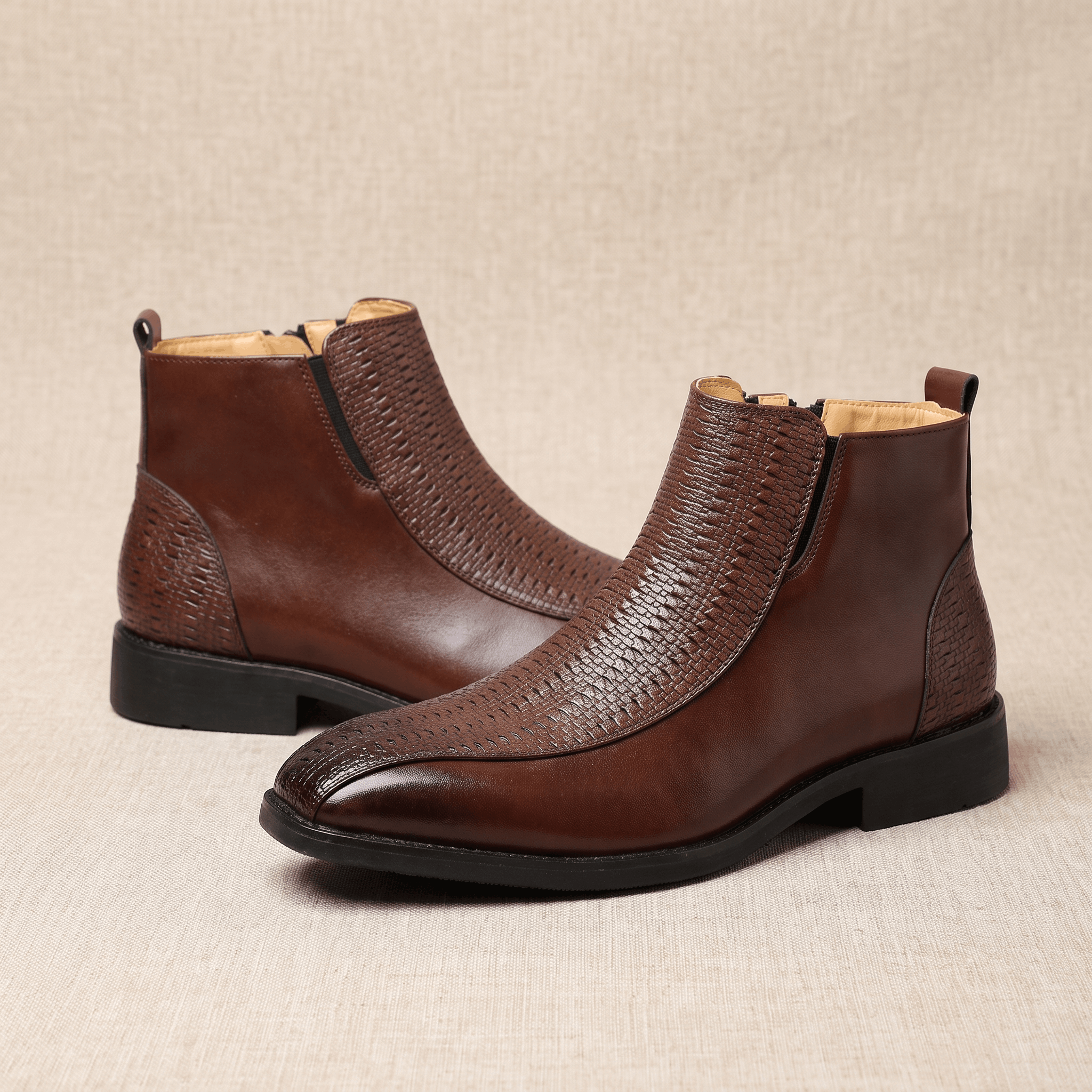Brown leather ankle boots with basketweave embossed panels, side zips, and a squared toe on a low stacked heel.