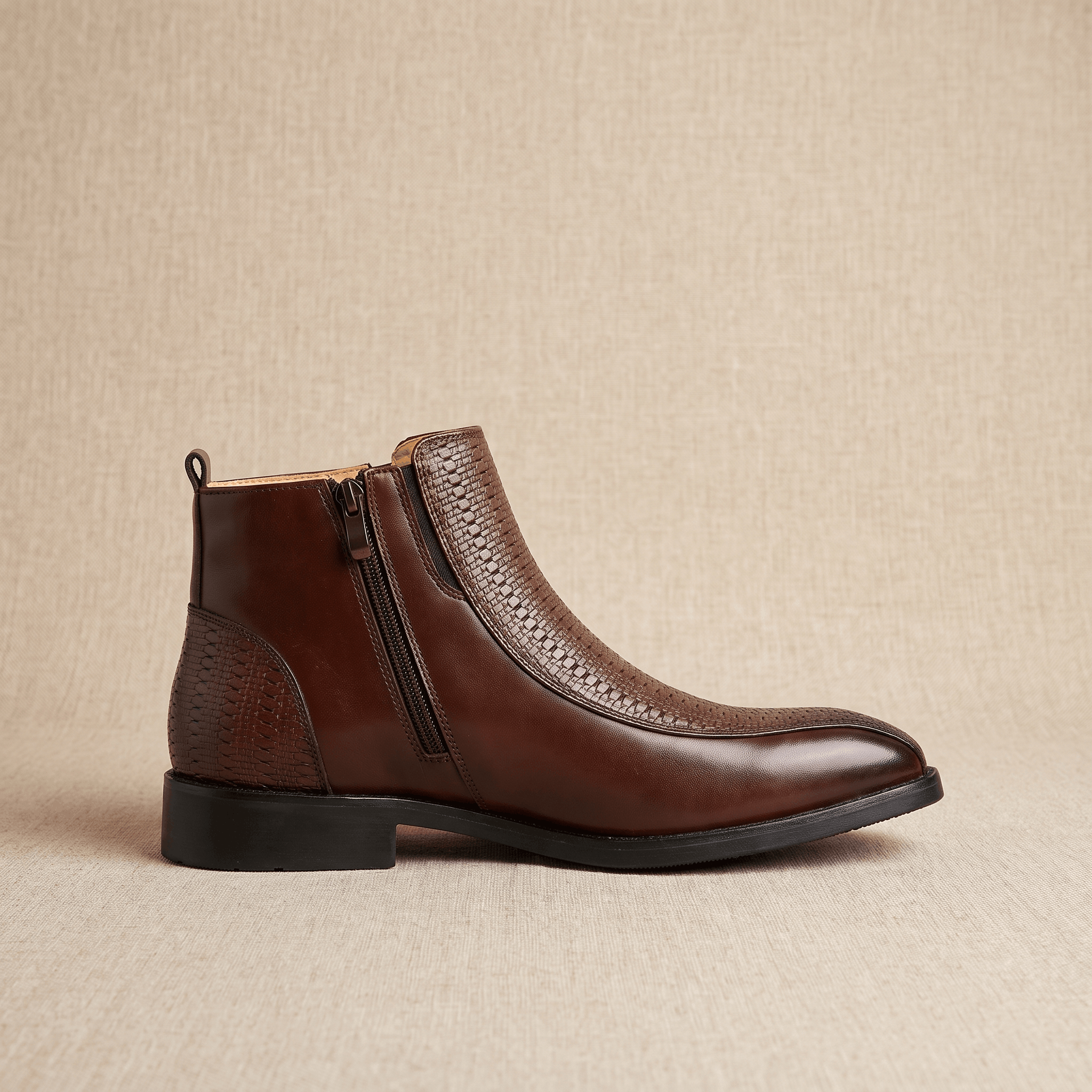 Brown leather ankle boot with basketweave embossed panels, side zip closure, and a low stacked heel with a squared toe.