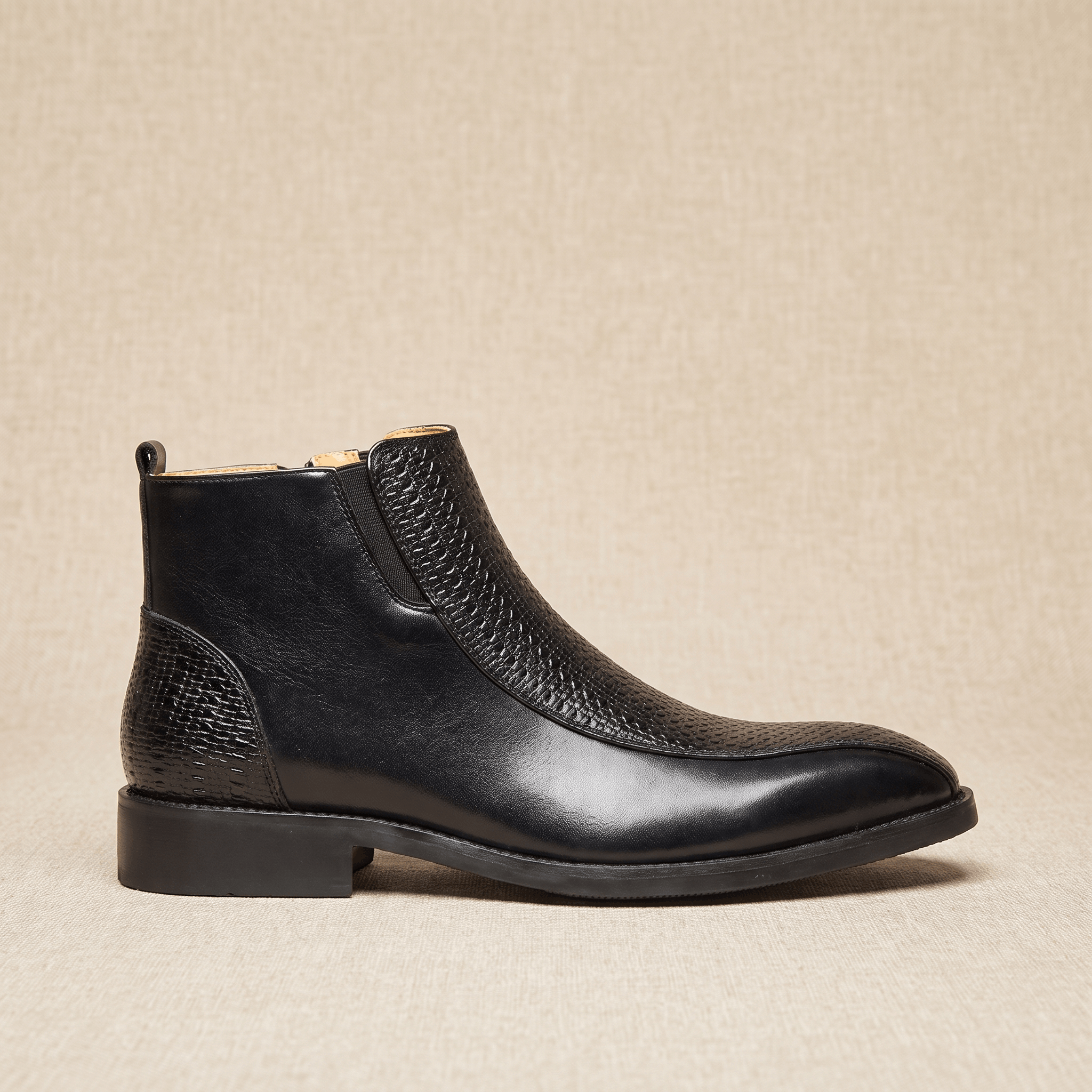 Black leather ankle boot with basketweave embossed panels, side zip, and a low stacked heel with a squared toe.