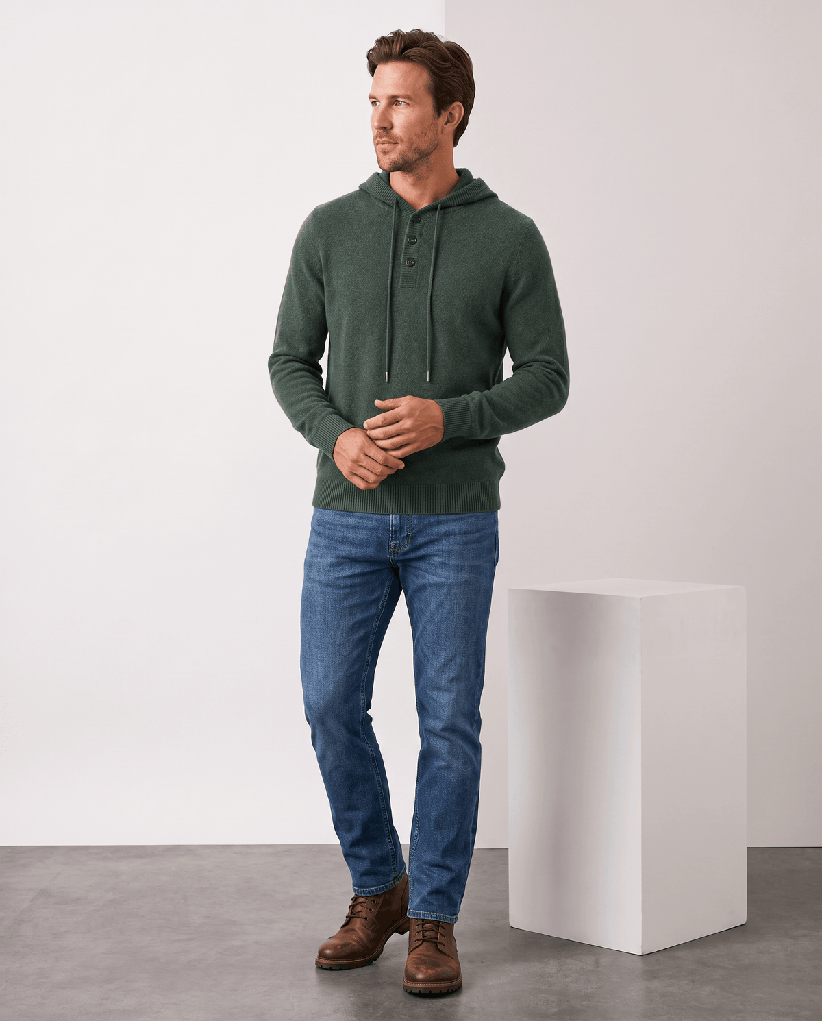 Full-length view of a man in a green knit hoodie, blue jeans and brown boots