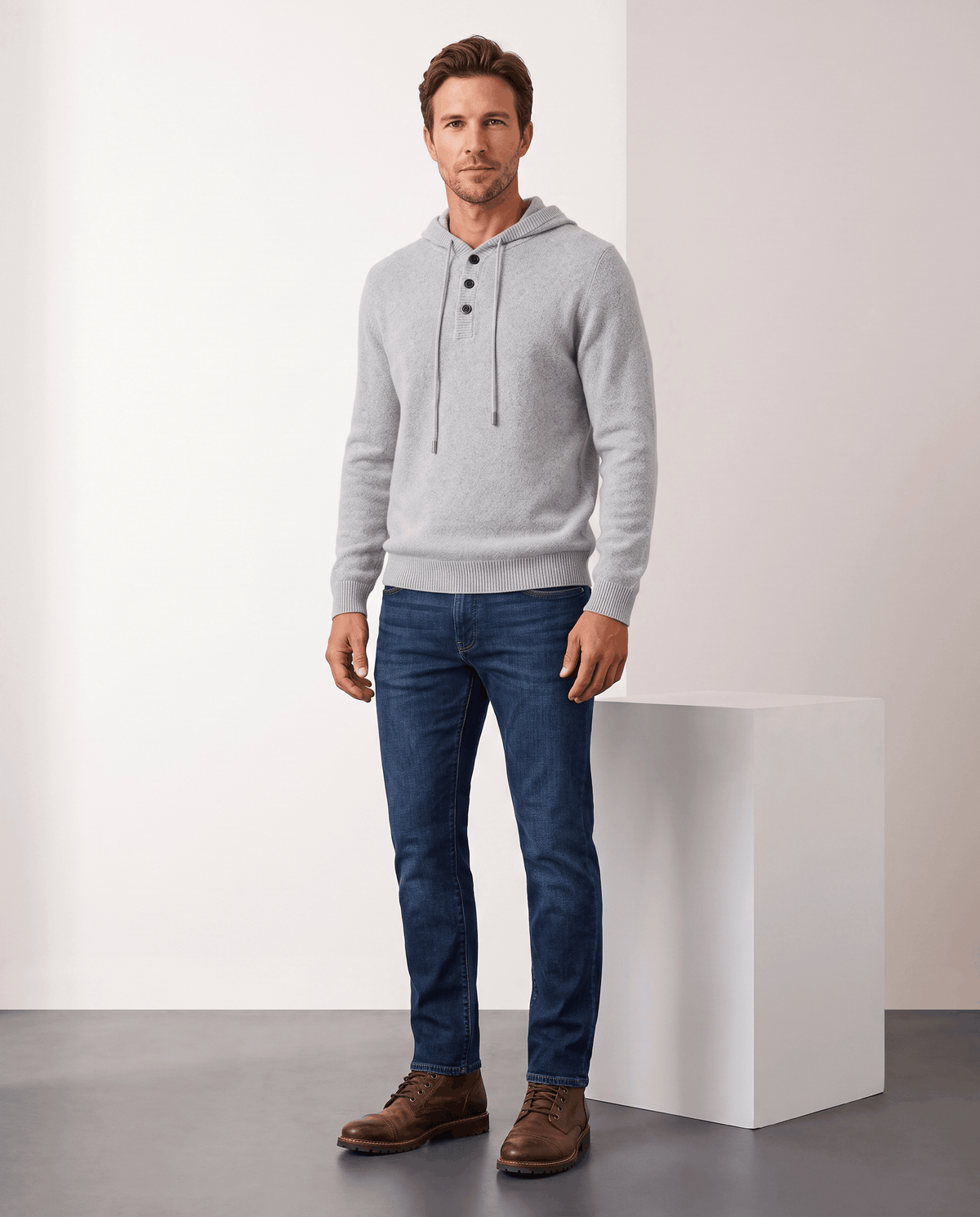 Full-length view of a man in a light gray knit hoodie, blue jeans and boots