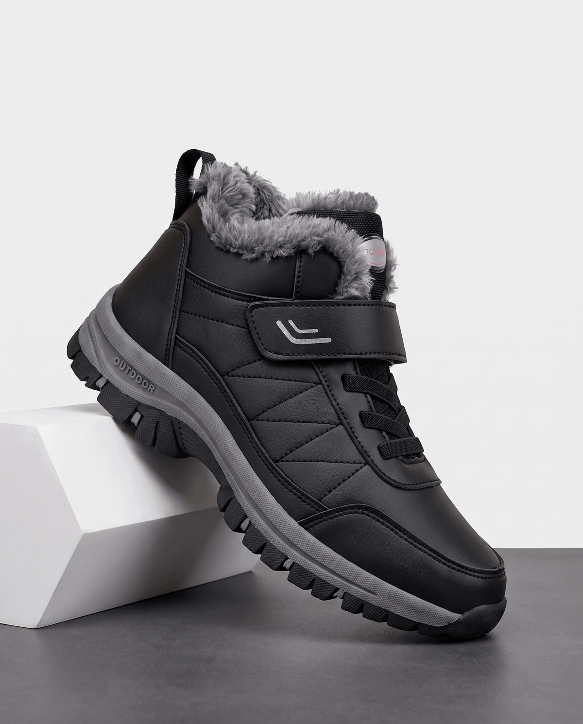 Black fleece-lined winter boot displayed on white blocks.