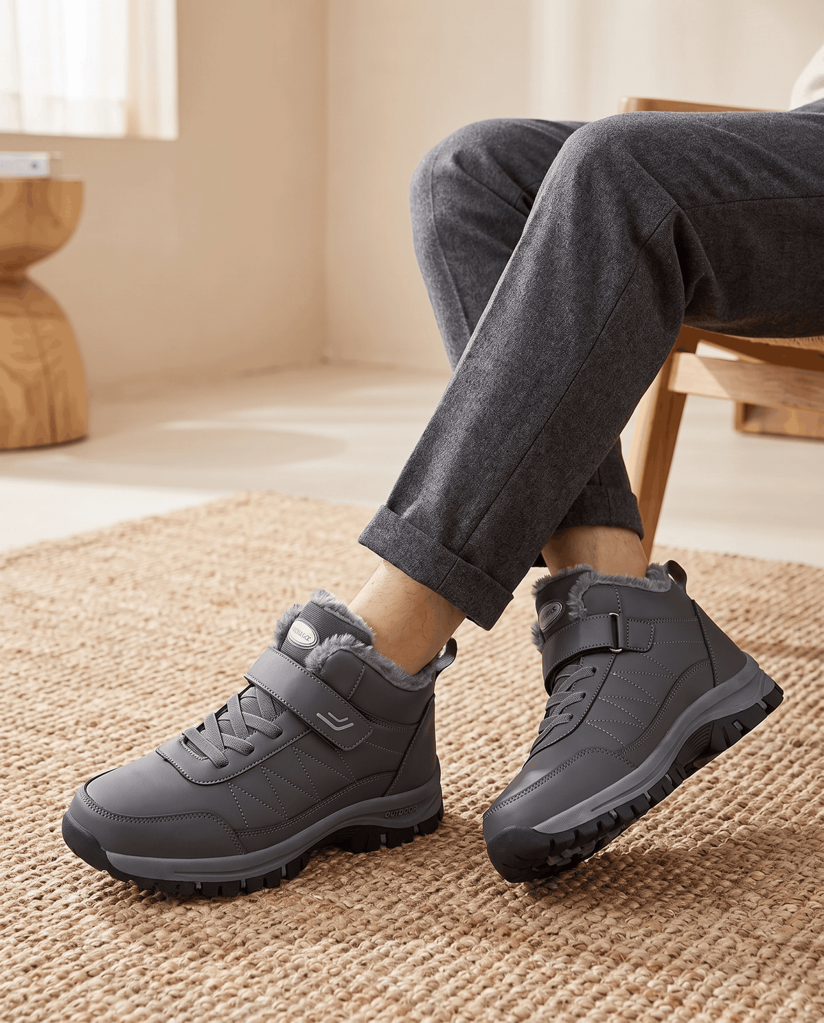 Person wearing gray winter boots with dark pants while seated indoors.