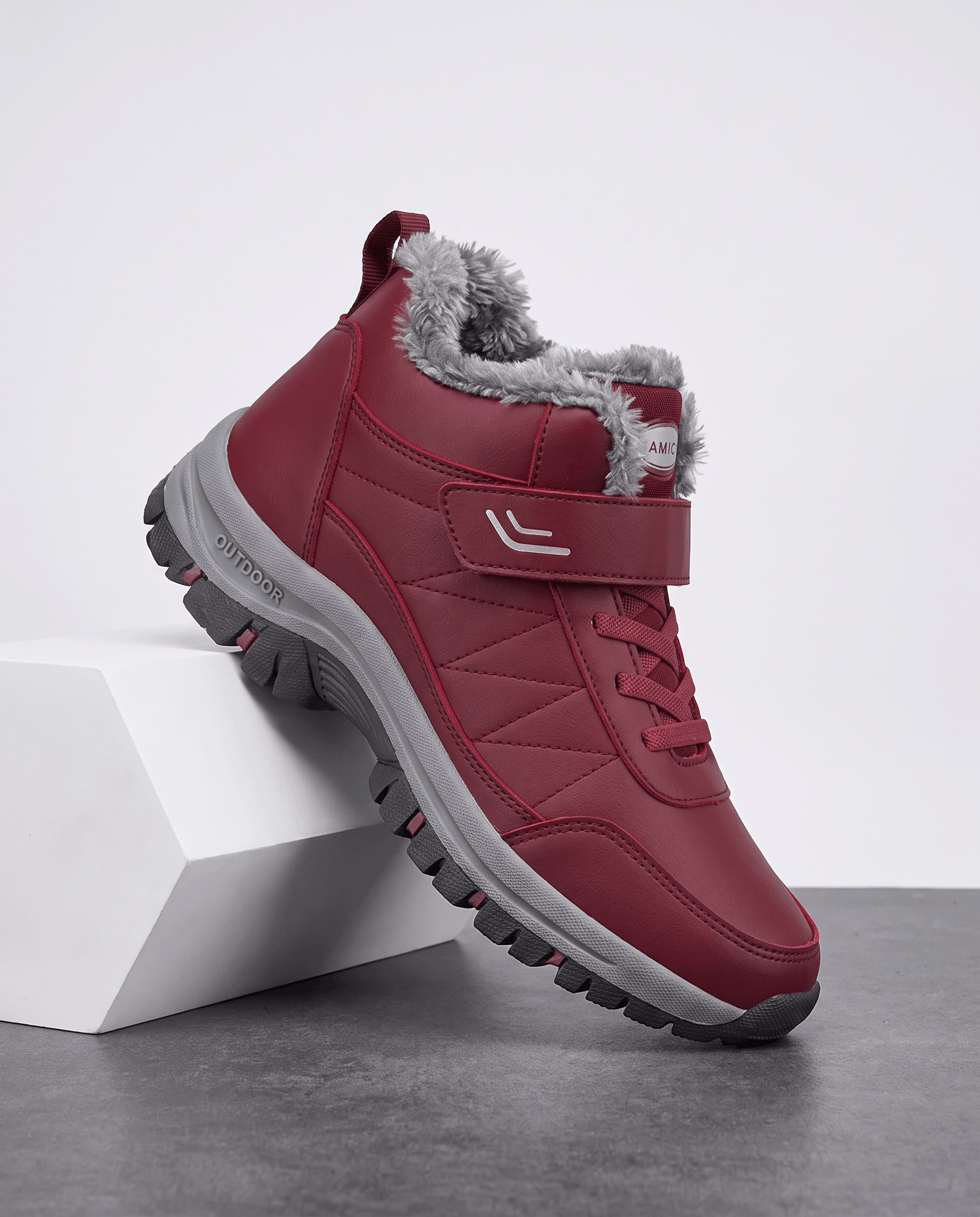 Red fleece-lined winter boot displayed on a white pedestal.