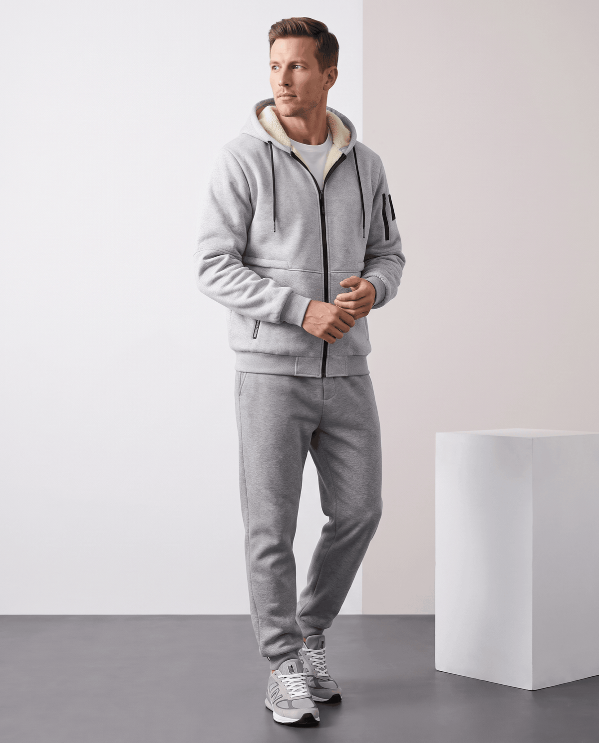 Full-length view of gray hooded jacket styled with gray joggers and light sneakers
