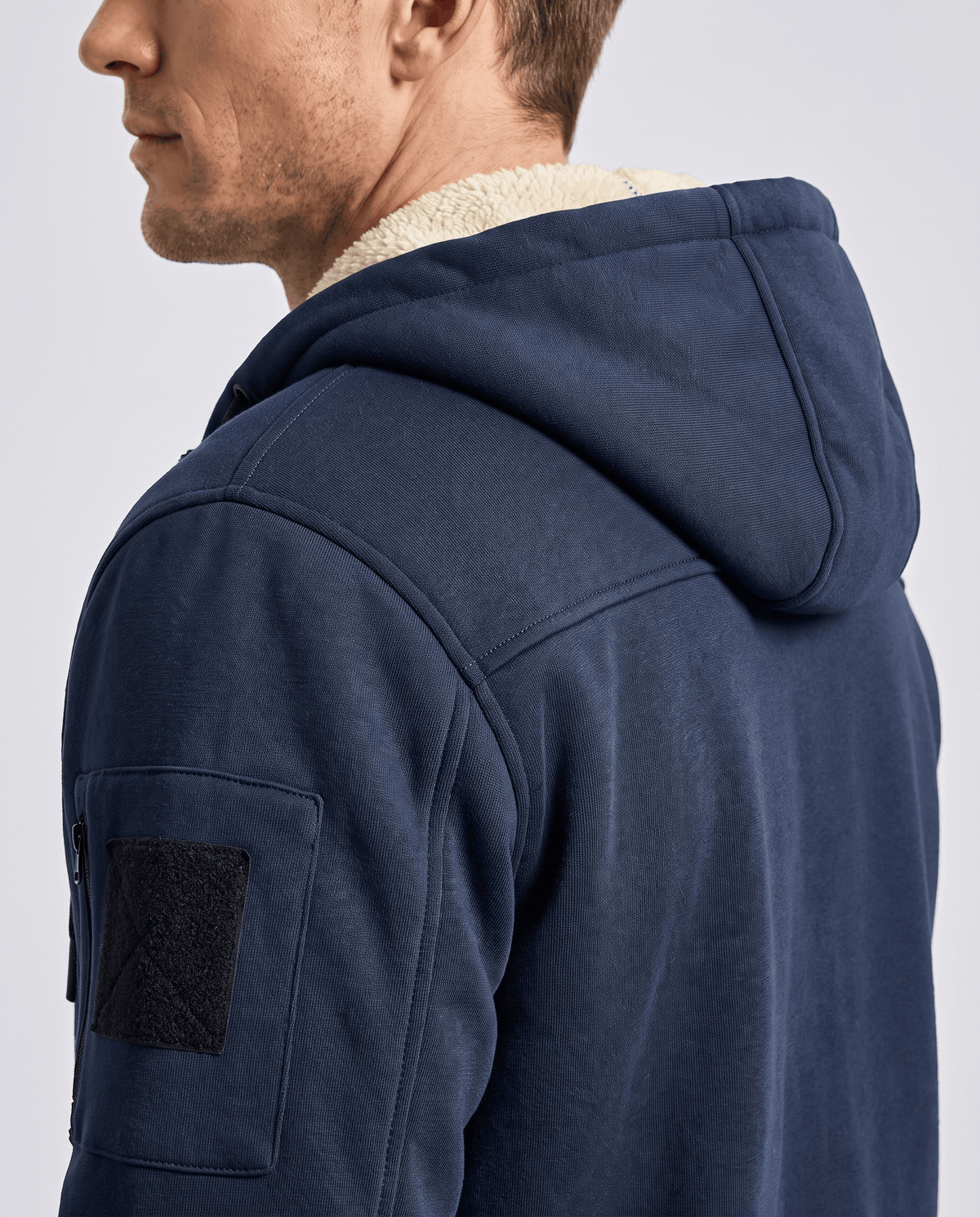 Side close-up of navy blue hood with fleece lining and the pocket on the sleeve