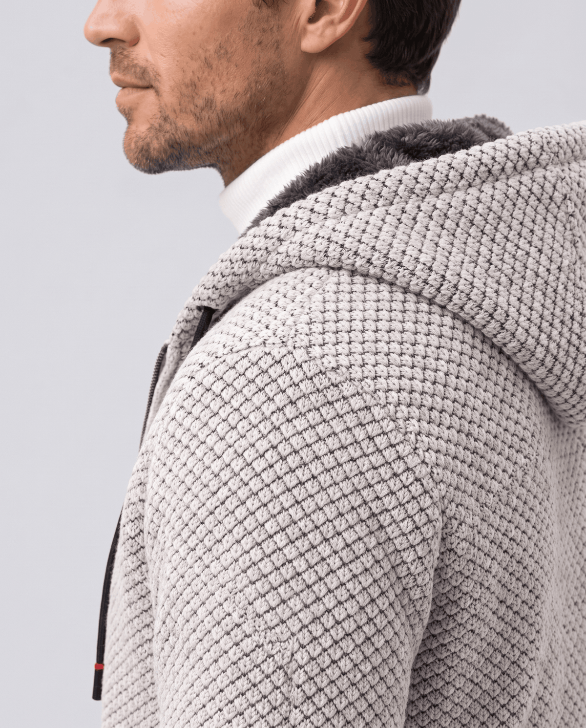 Side profile of a beige knit hoodie showing the textured knit and hood